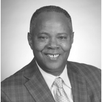 Black man in a suit smiling, black-and-white photo.