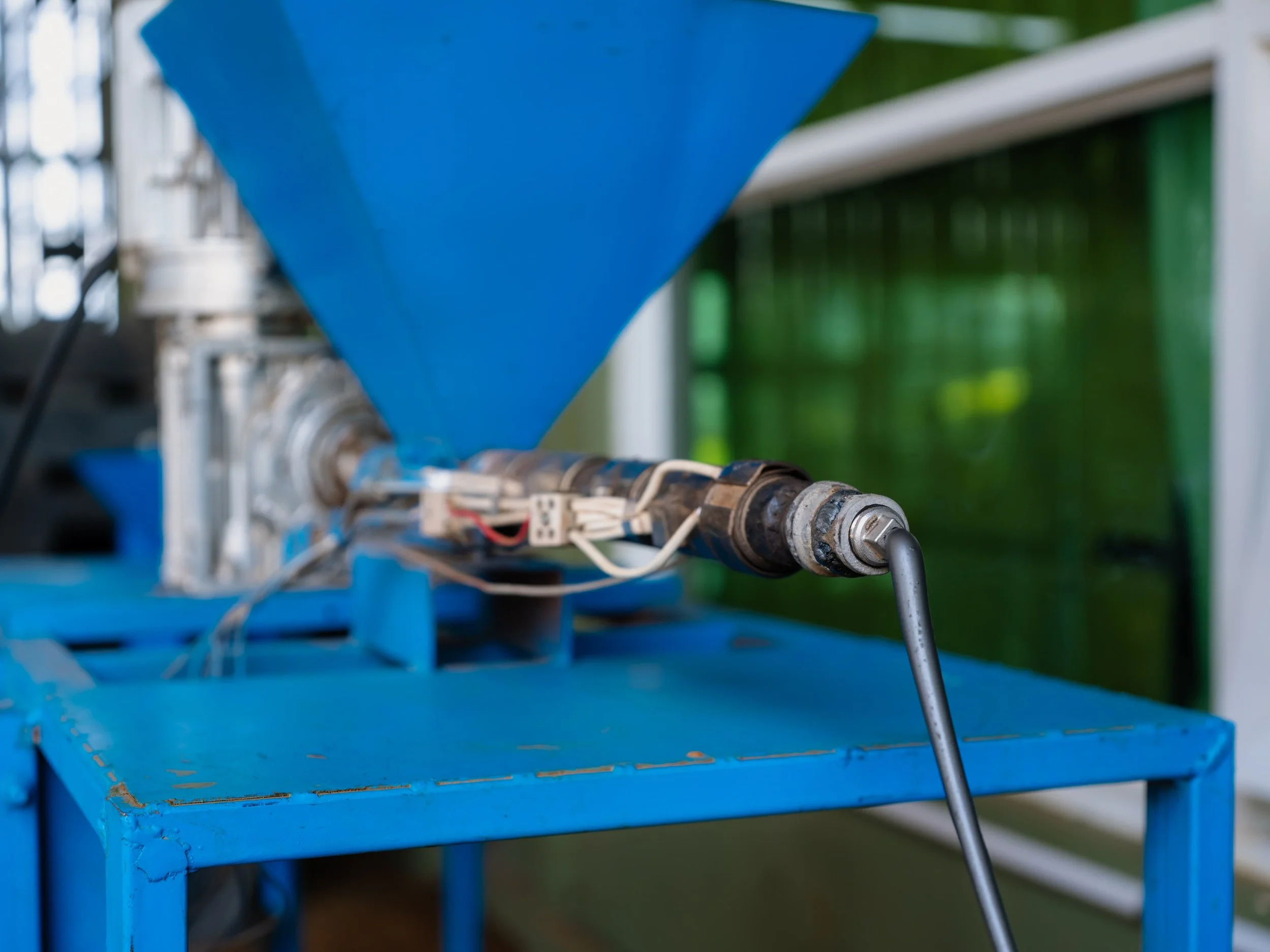Close-up of a blue industrial machine with mechanical parts and wiring, possibly used for manufacturing or processing.