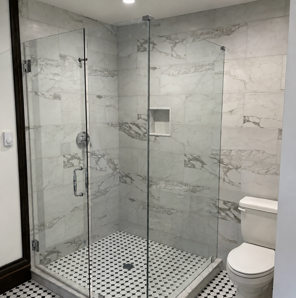 Bathroom with glass shower enclosure and a toilet, featuring marble tiles and a black and white hexagonal tile floor.