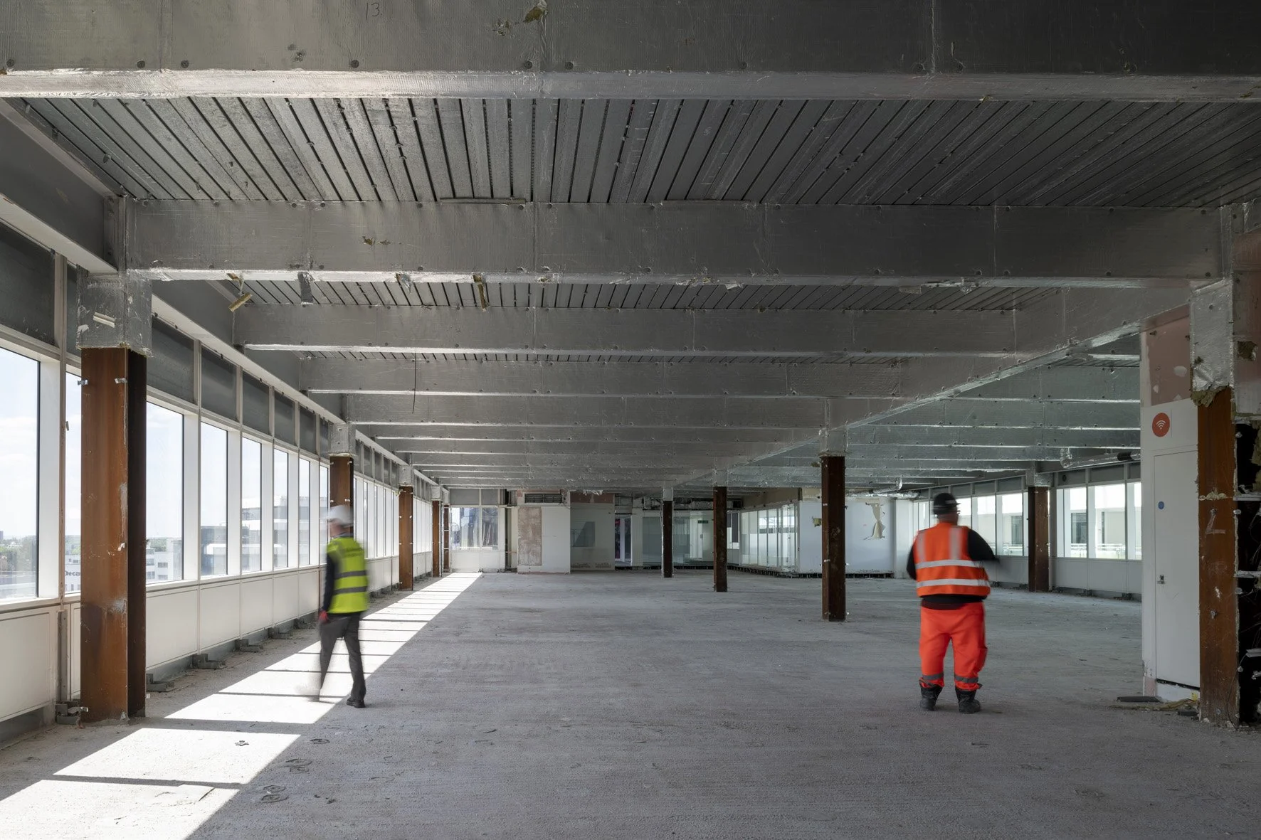 Hi-vis worker inspecting a stripped-out commercial building interior