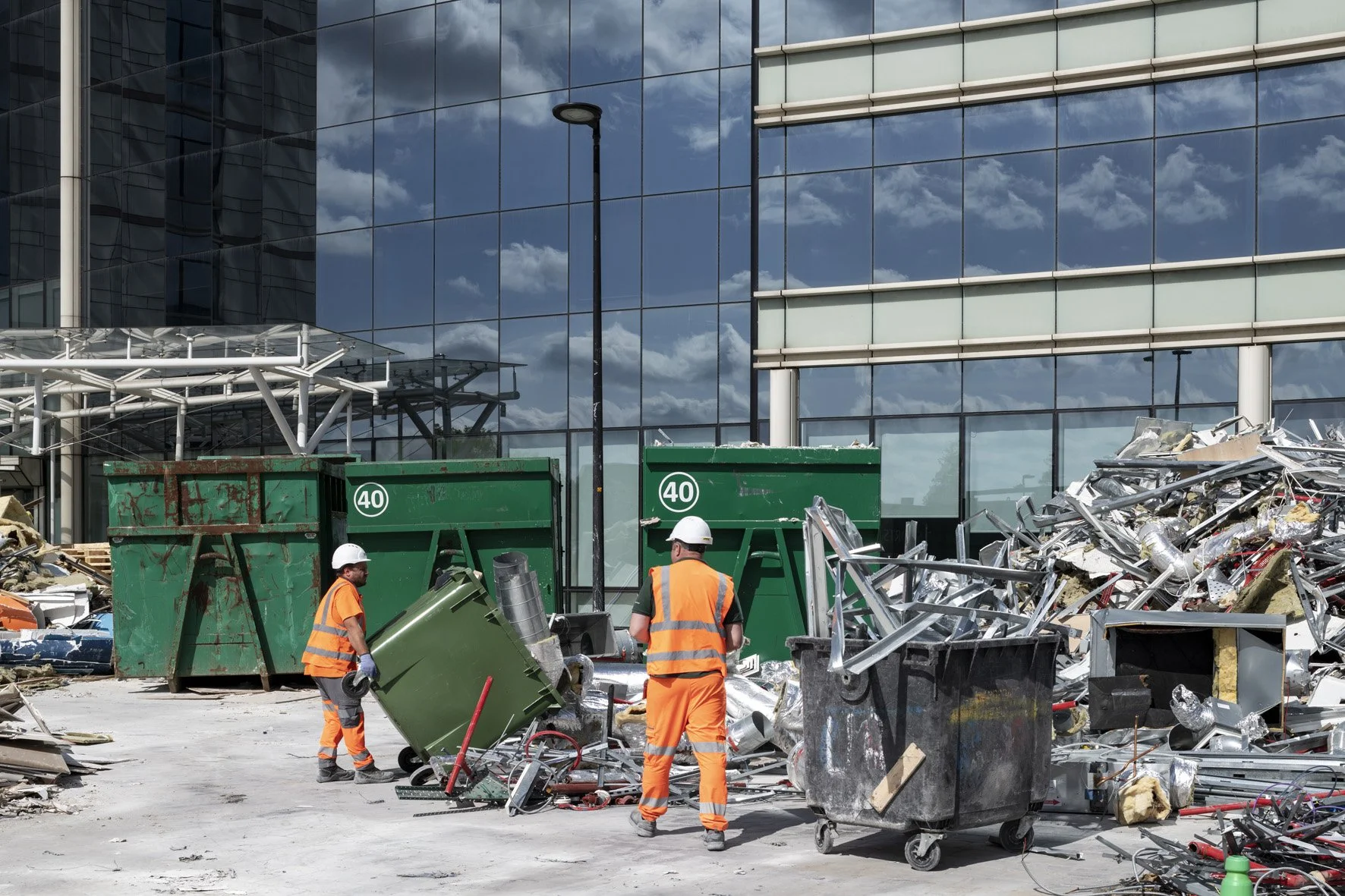 Workers loading construction waste skips during a pre-demolition audit for material recovery and recycling