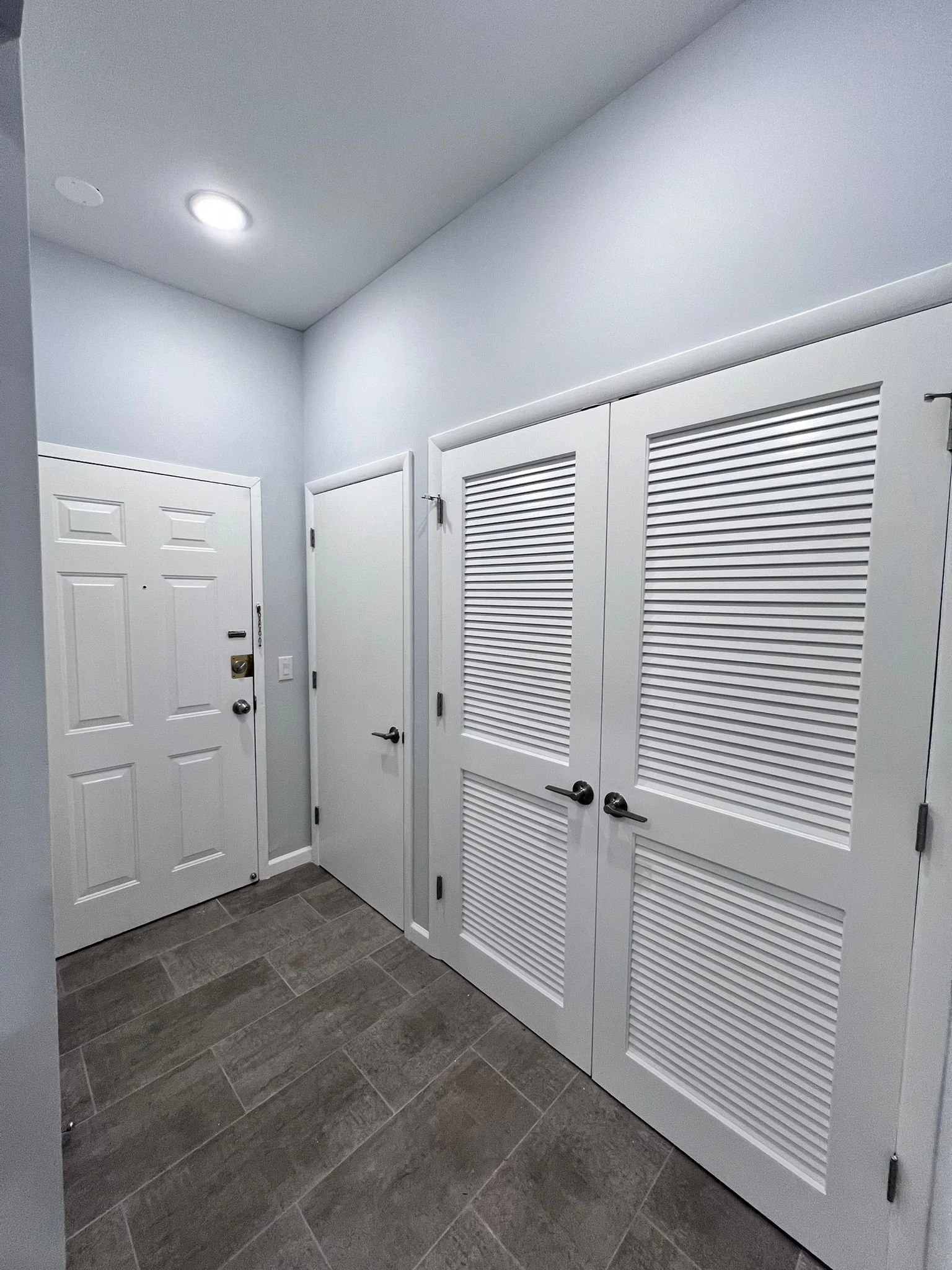 New laundry room with new louver doors, new tile floor, new entry doors, new trim, and mouldings