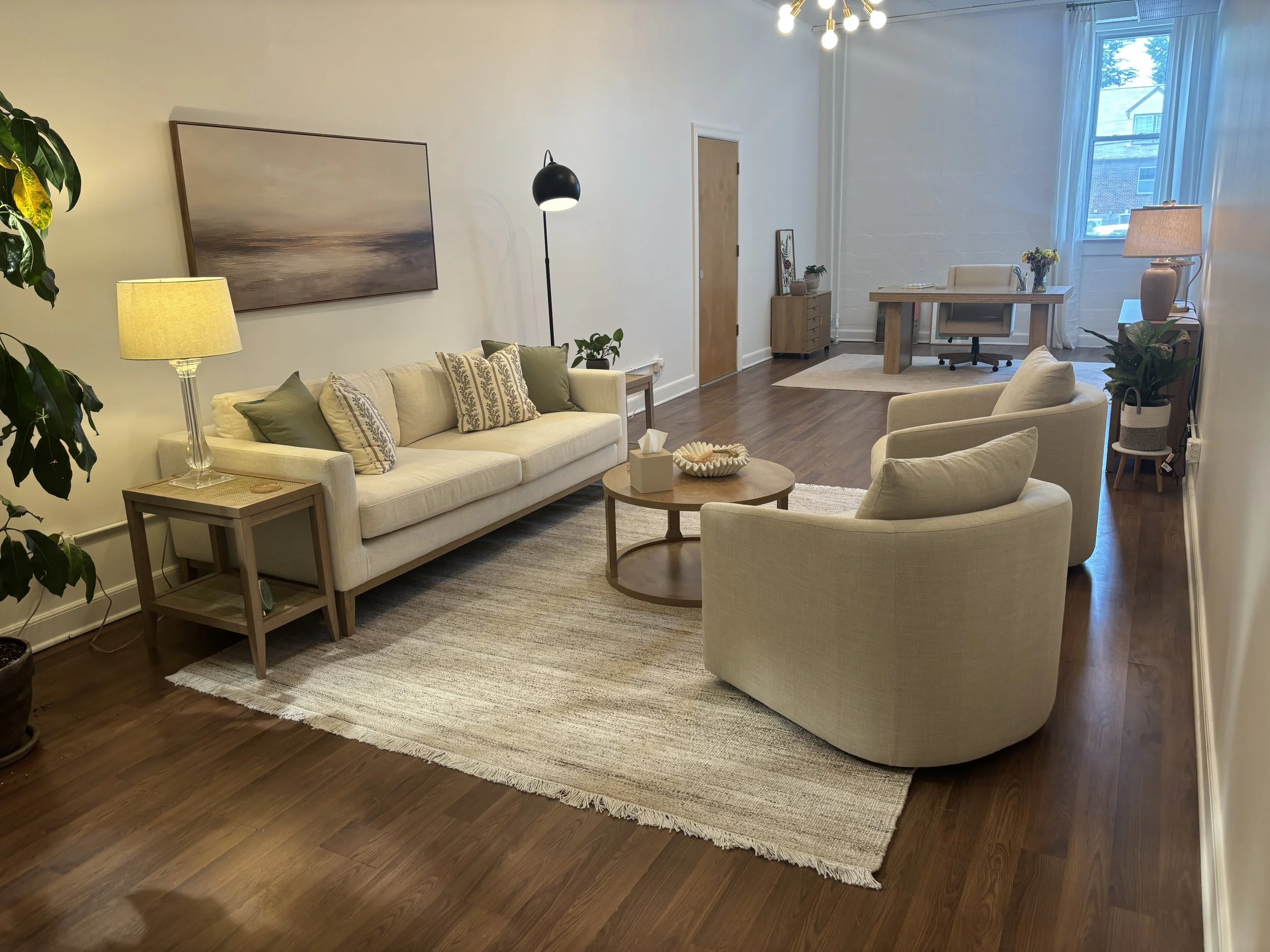Angela Muterspaugh, LMFT, Integrative Psychotherapy Therapy office space with a beige sofa, armchairs, plants, and natural light