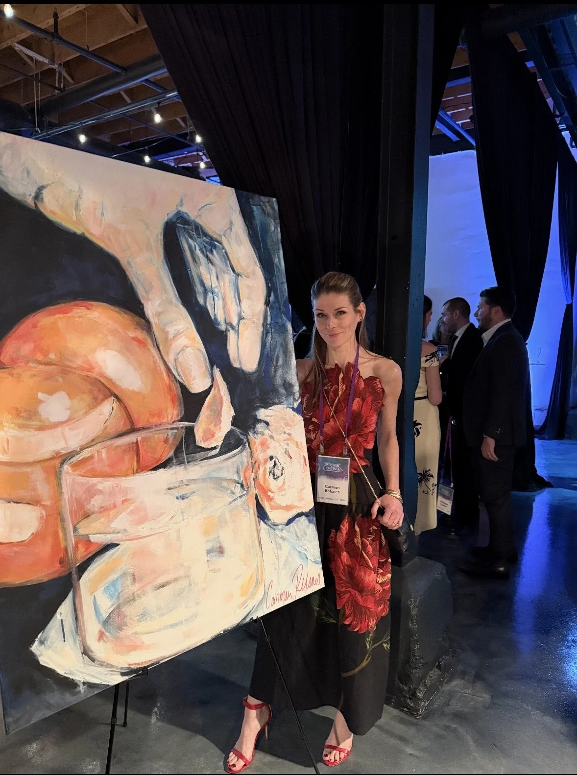 Carmen Refsnes, contemrporary artist, poses in Farm Rio dress at Anixter Center Gala next to her artwork, Choices. One of three, of the Balance of Power series.
