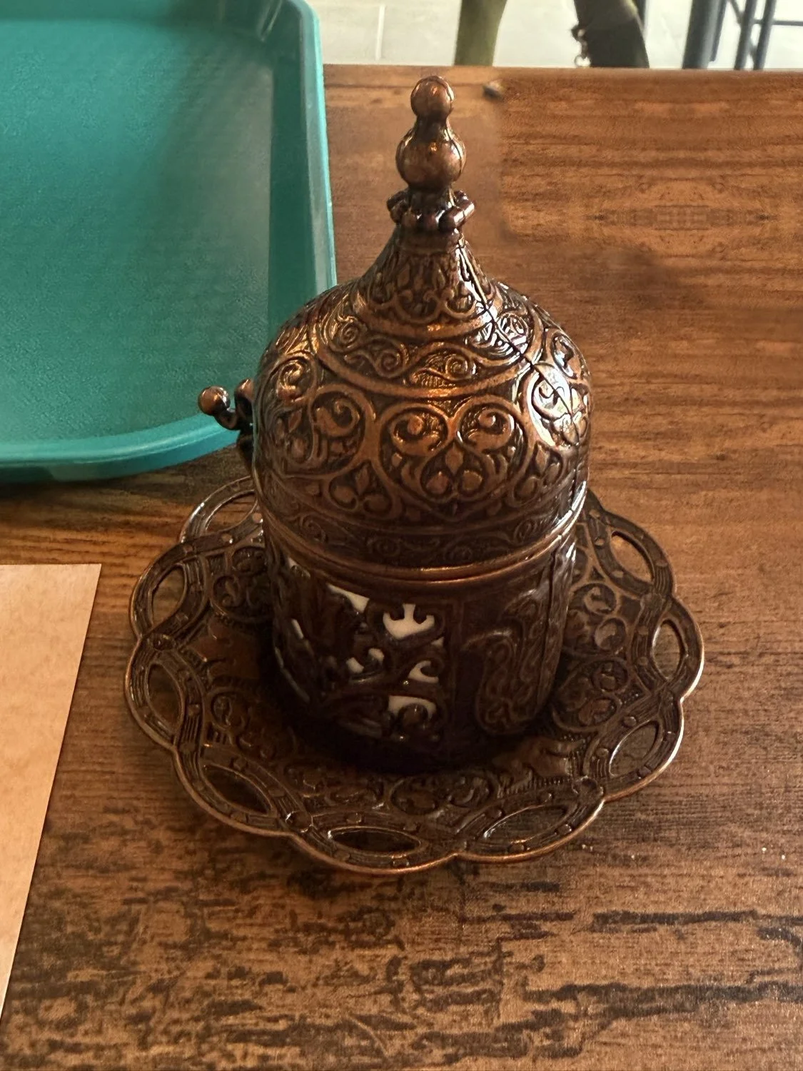 Ornate copper Turkish lidded cup and saucer on a wooden table at Clay Pot in Naples