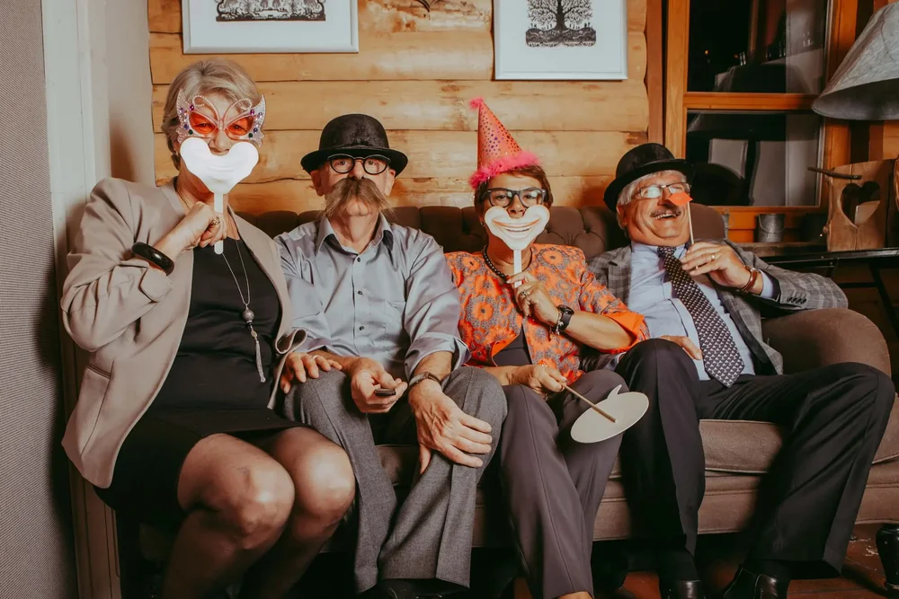 Vier Gäste mit Masken und Fotobox-Requisiten auf einem Sofa