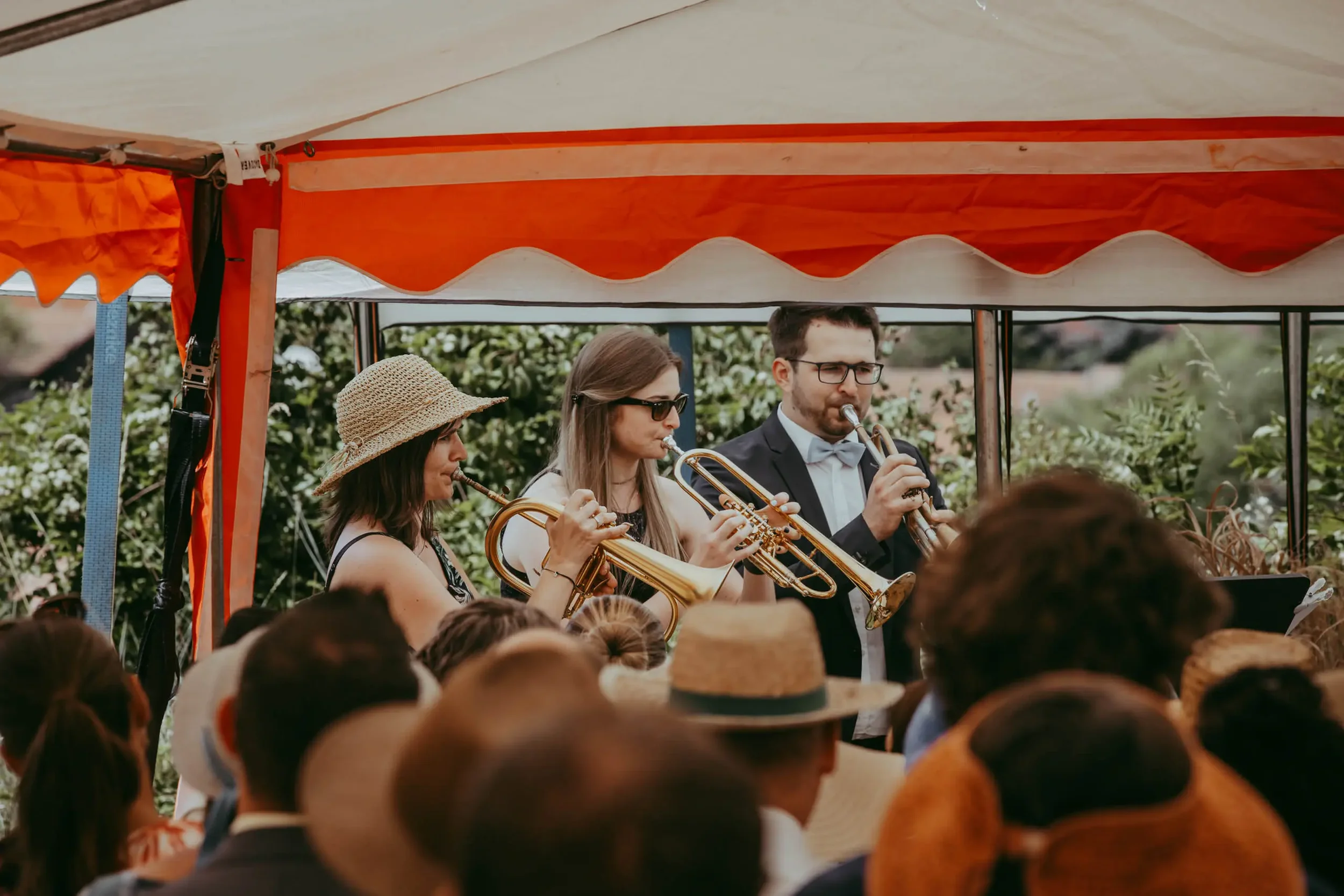 Musiker spielen auf einer Bühne bei einem Fest, Menschen im Publikum schauen zu.