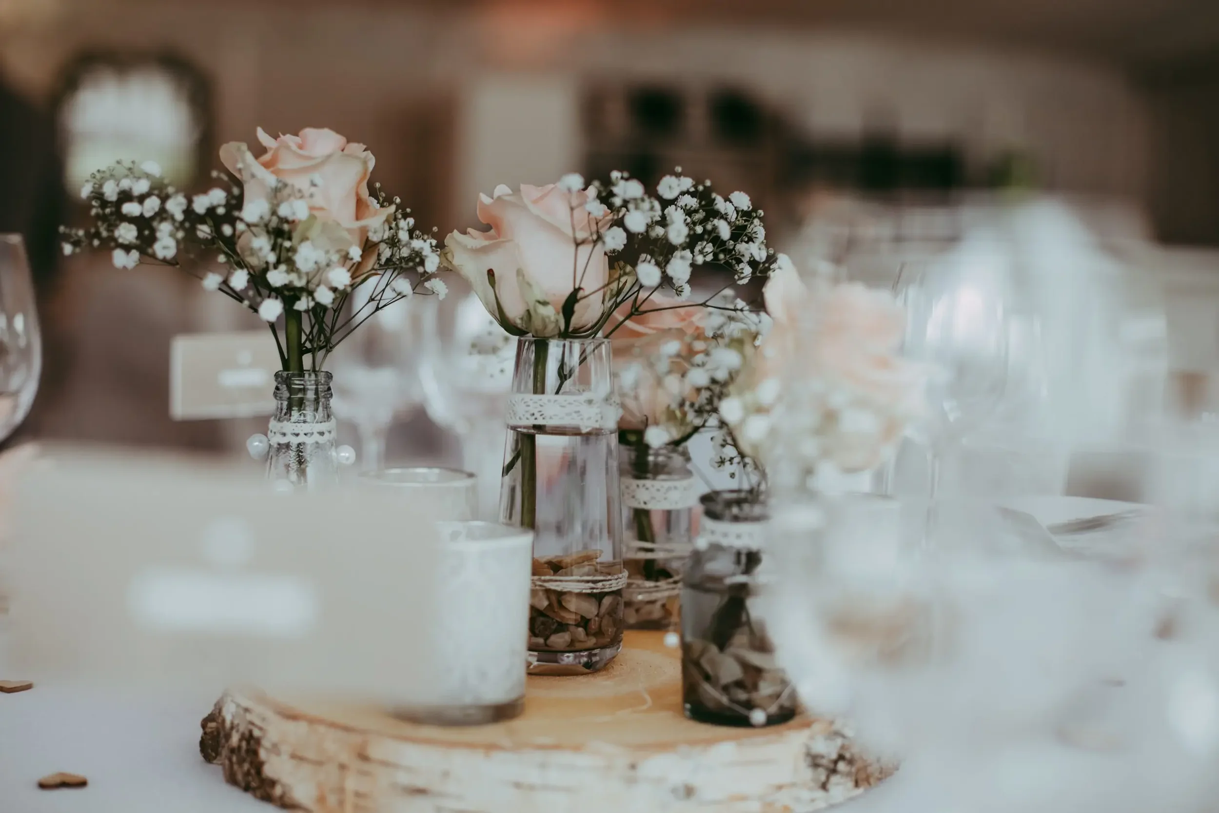 Blumenstrauß auf einer Hochzeitstafel mit Kerzen und dekorativen Gläsern.