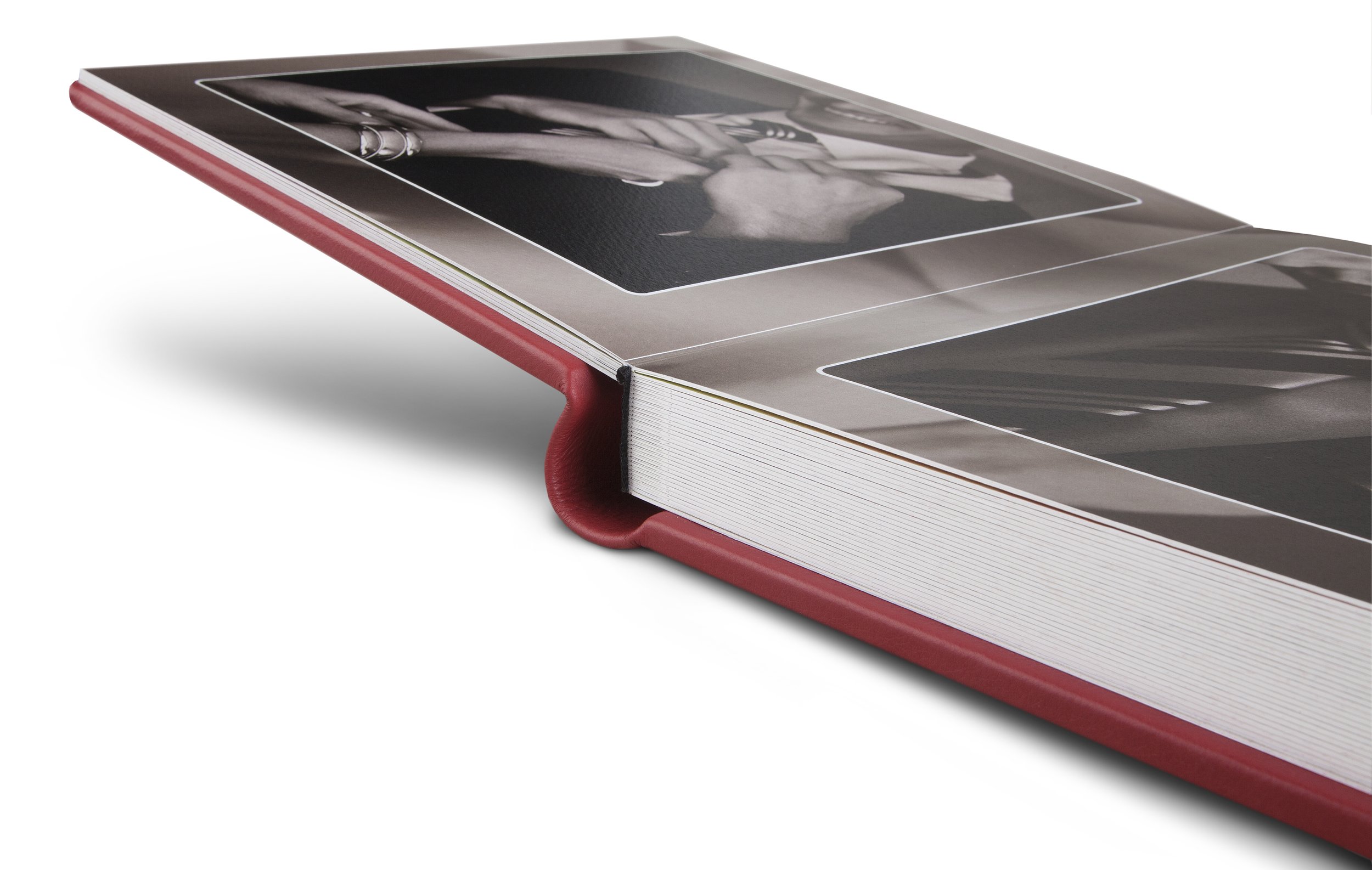Ein offenes Fotobuch mit Schwarz-Weiß-Fotografien auf weißen Seiten, Einmanndrucke sind sichtbar, roter Einband.