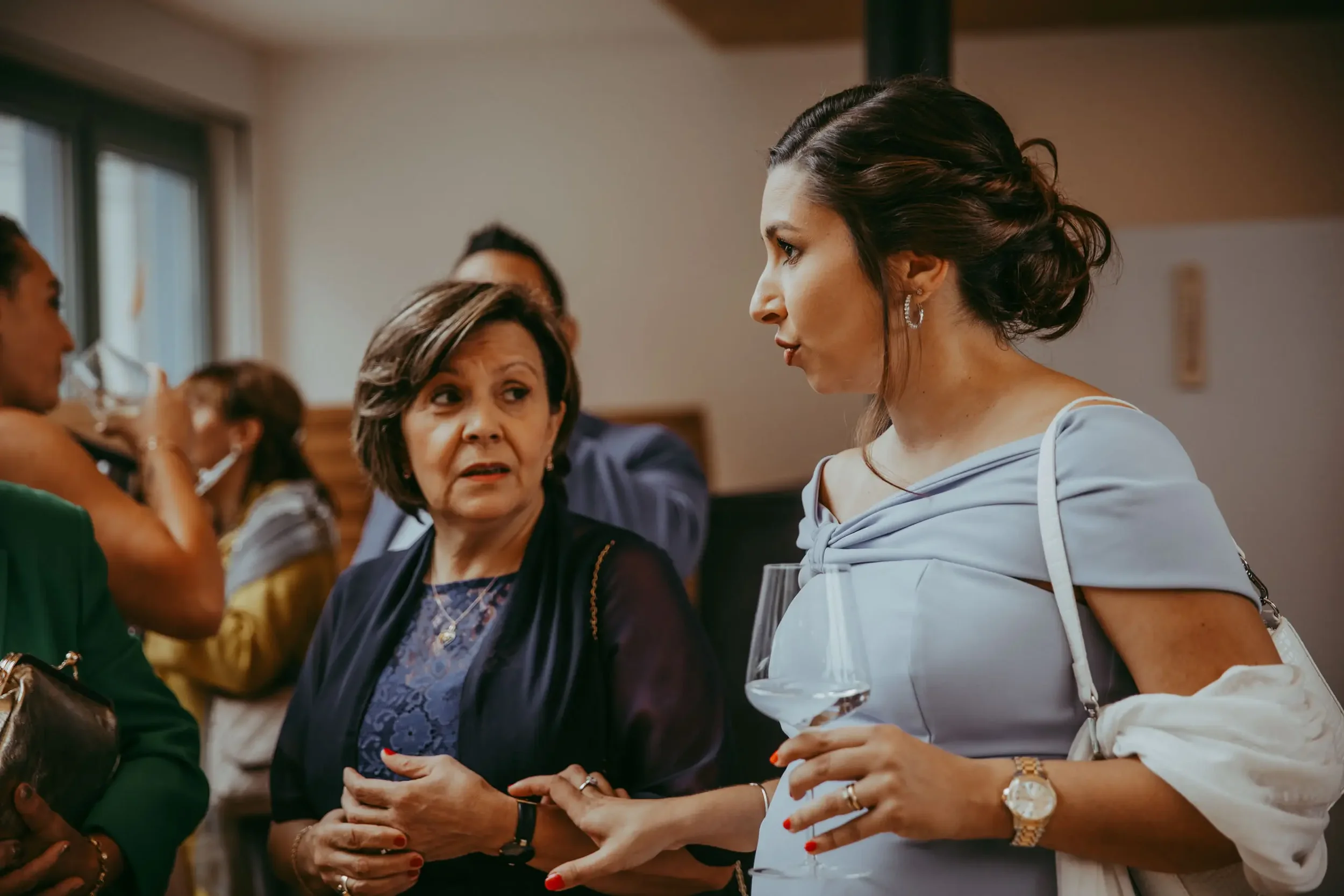 Eine Gruppe von Frauen im Gespräch bei einer Veranstaltung. Im Vordergrund eine junge Frau mit dunkelbraunen Haaren, blauer Bluse und Taschenlampe in der Hand, die mit einer älteren Frau spricht.