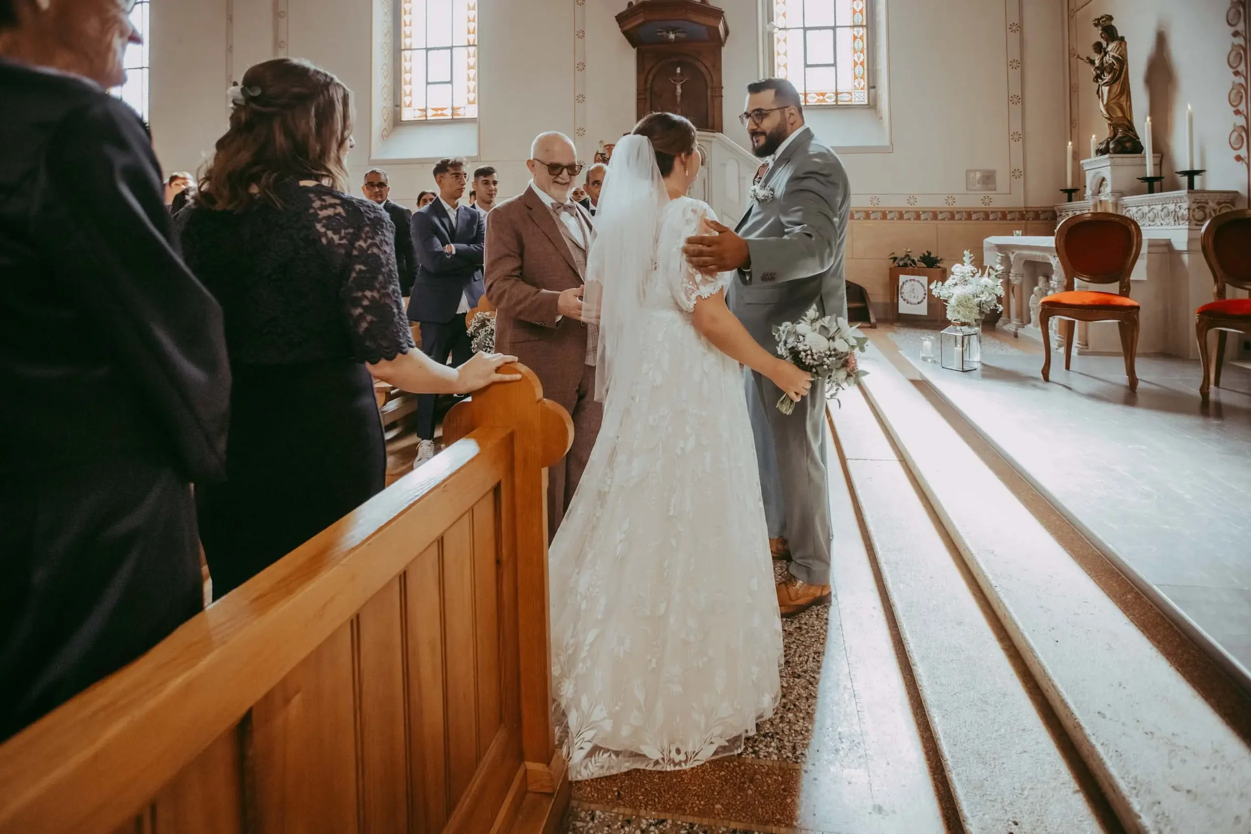 Ein Brautpaar bei einer standesamtlichen Trauung in einer Kirche, umgeben von Freunden und Familie.