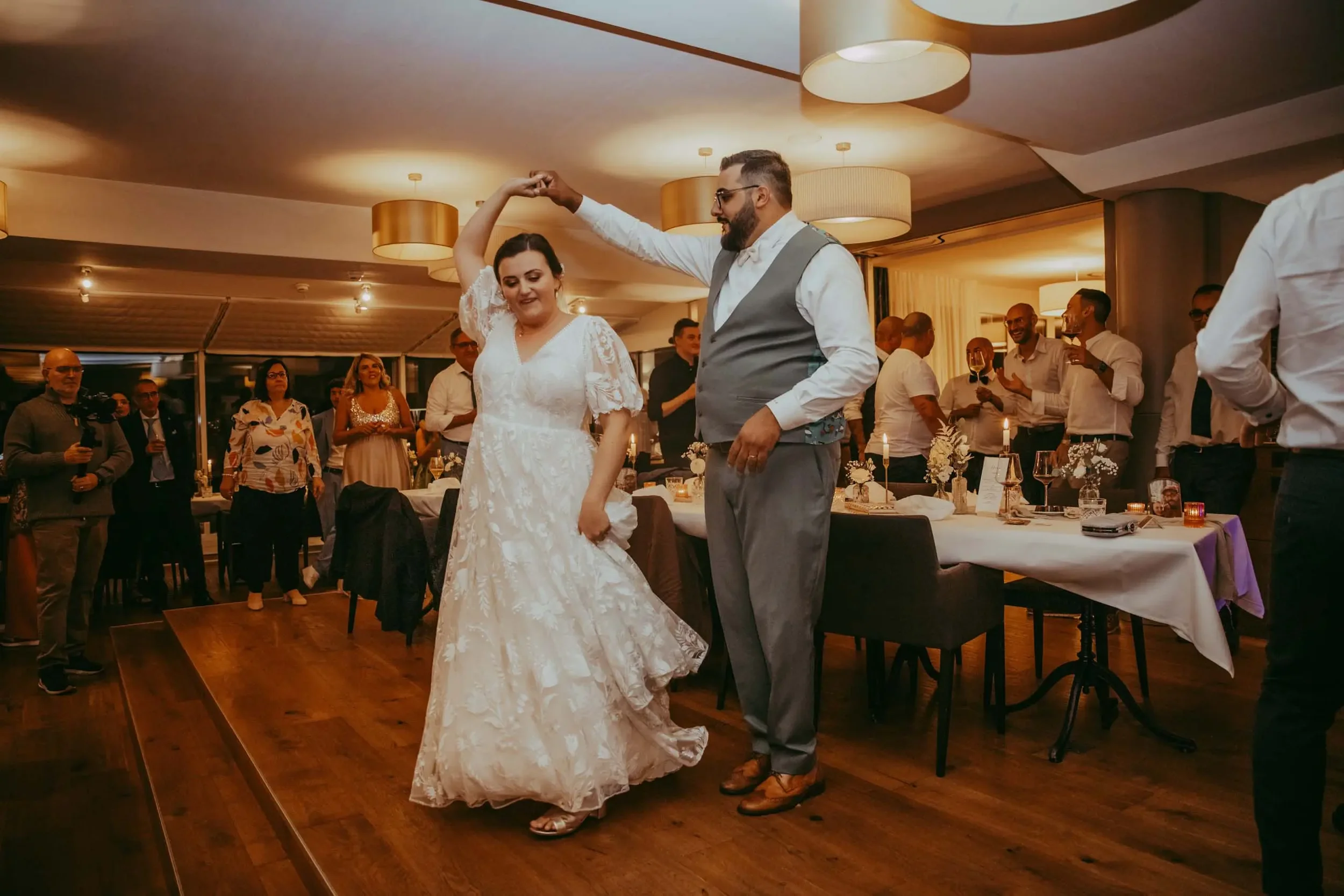 Ein Brautpaar tanzt auf einer Hochzeitsparty im festlich dekorierten Raum, umgeben von Gästen, die das Fest genießen.