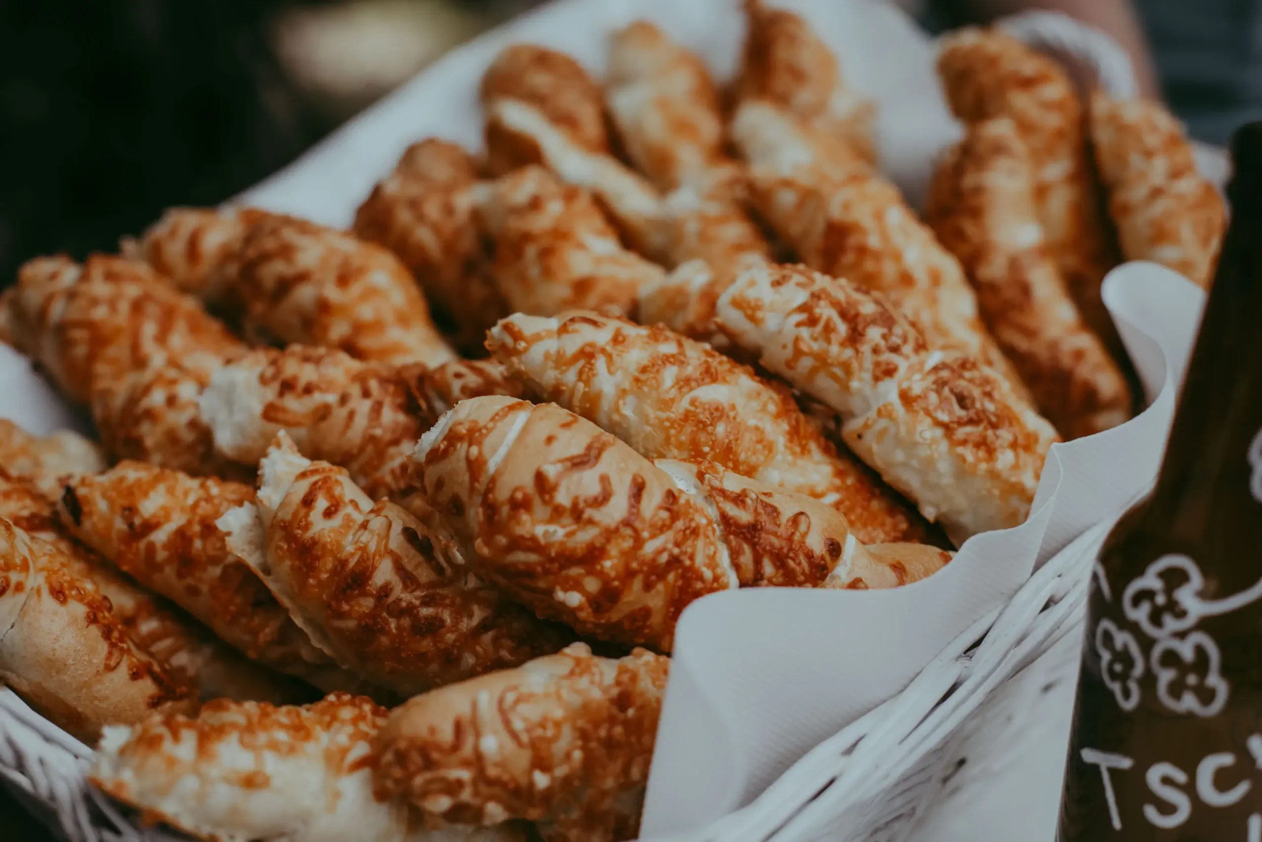 Nahaufnahme von frisch gebackenen, mit Käse überbackenen Snacks in einer Pappschale