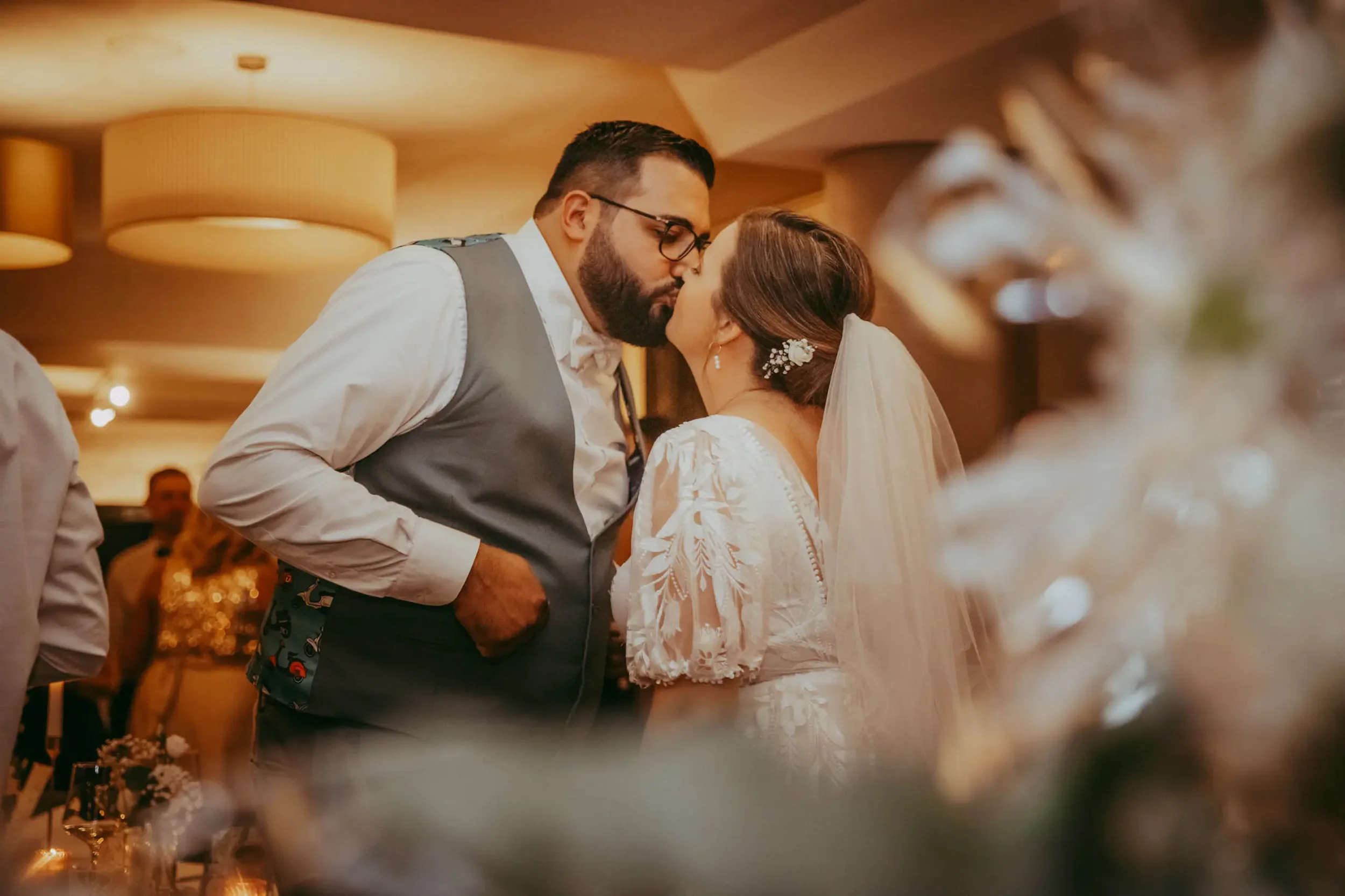 Ein Brautpaar küsst sich bei einer Hochzeit in einem festlich dekorierten Raum.