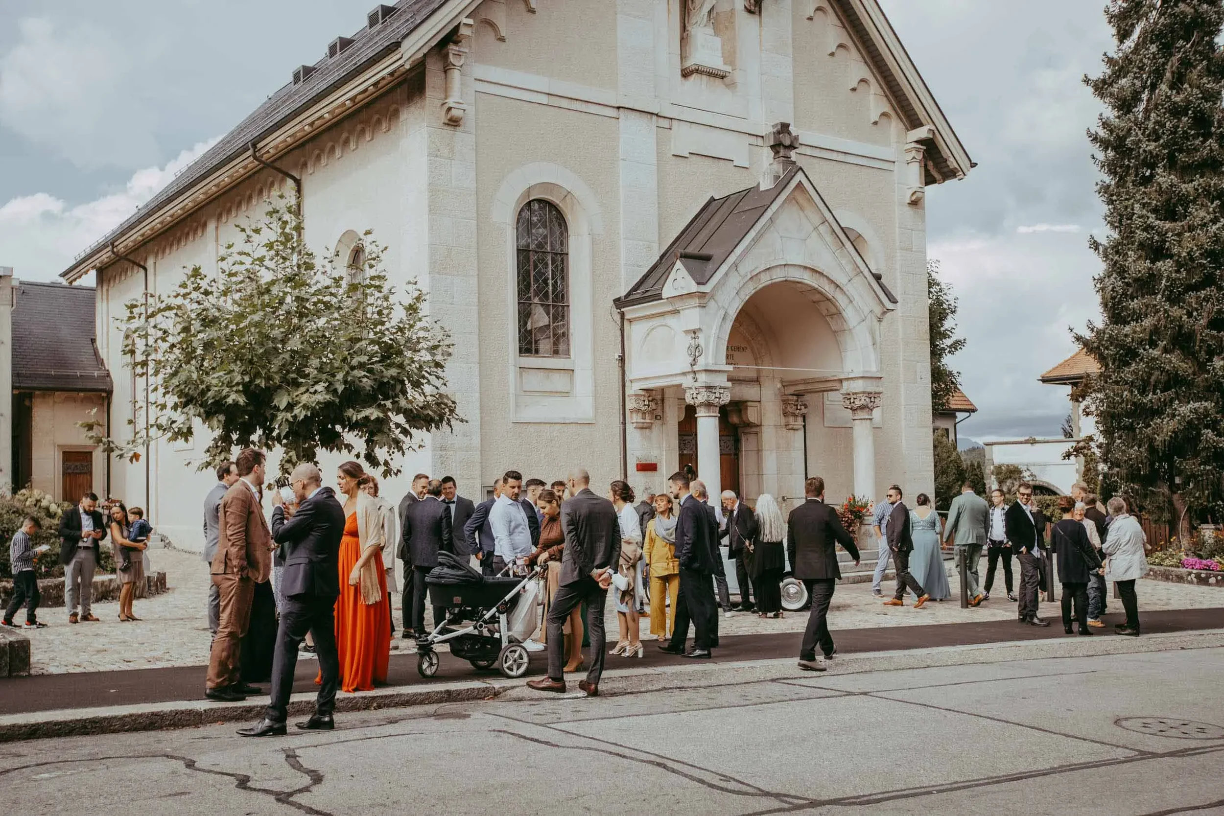 Menschen versammeln sich vor einer alten Kirche bei einem Event oder einer Feier.