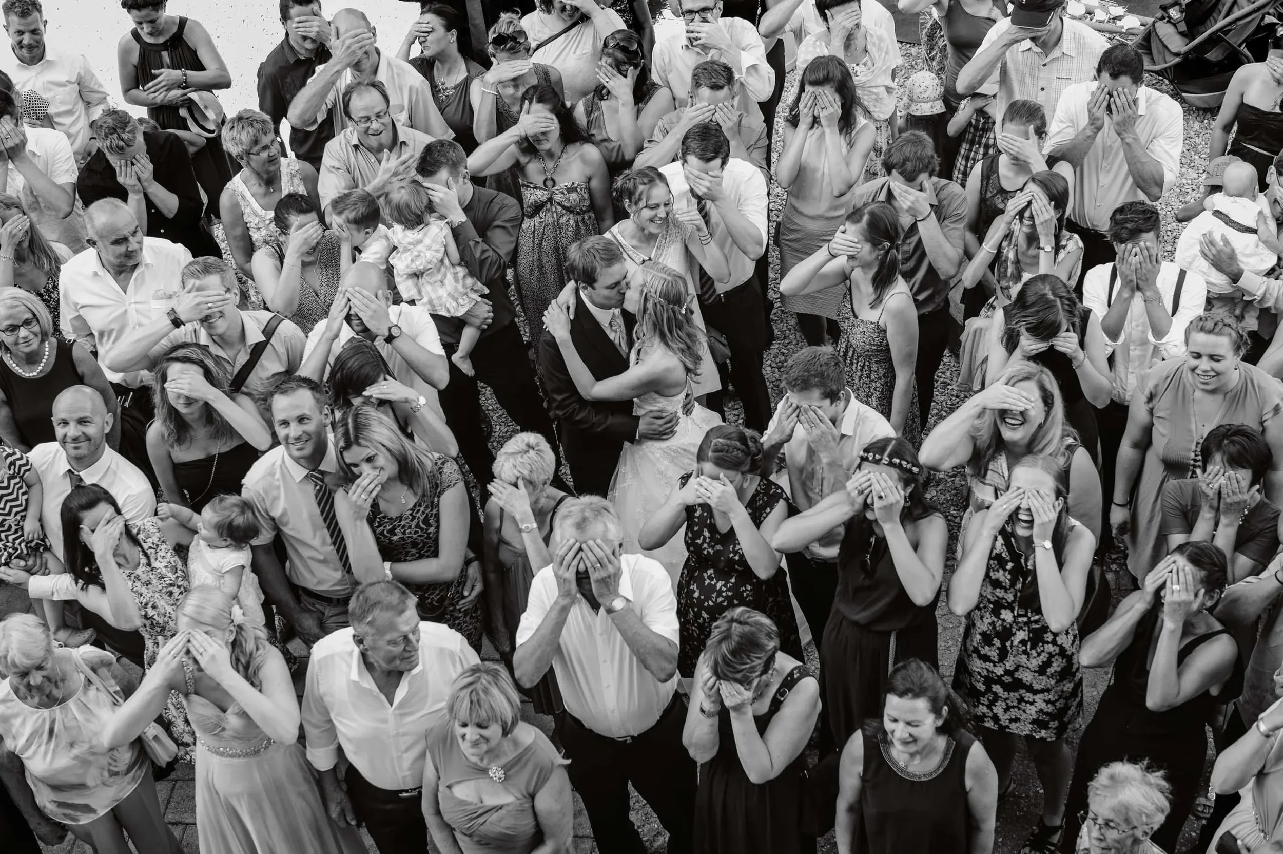 Eine Gruppe von Menschen steht dicht beieinander, alle haben die Hände vor den Augen und scheinen an einer gemeinsamen Emotion wie Trauer oder Nachdenklichkeit teilzunehmen.