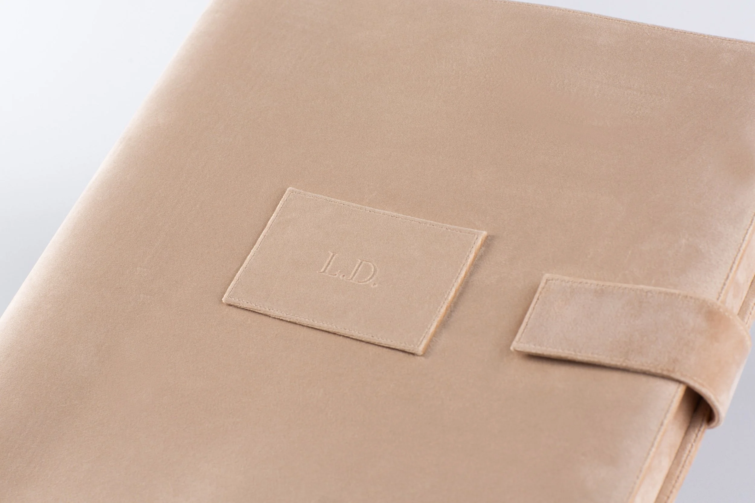 Nahaufnahme eines beige Ledersacks mit einer Tasche mit eingesticktem Anfang 'L.D.'.