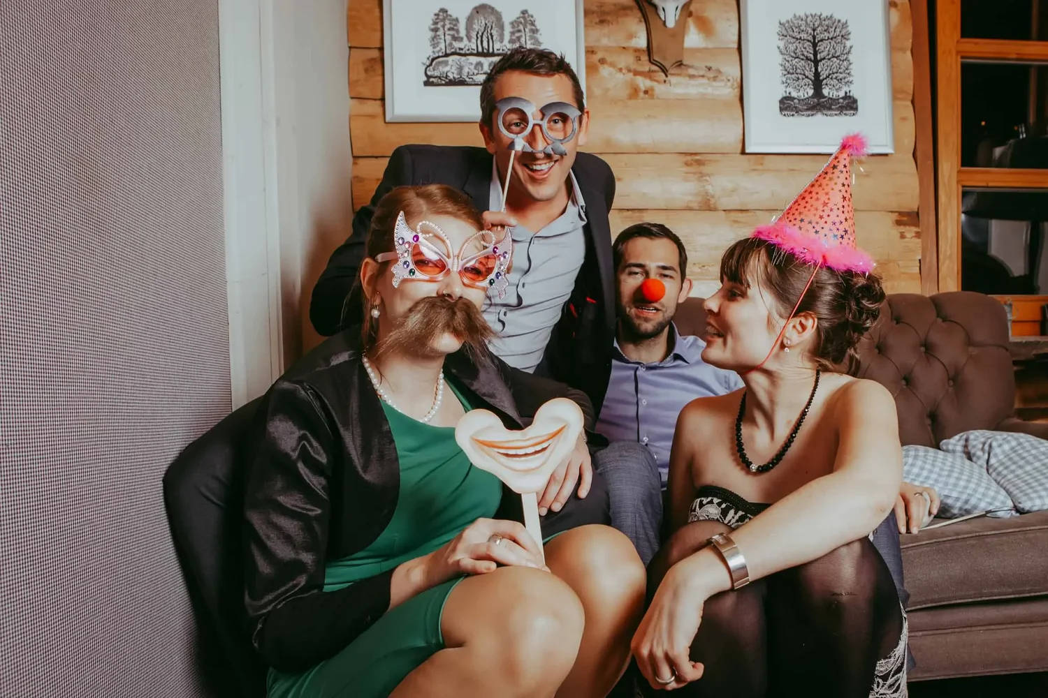Vier Hochzeitsgäste posieren mit Brillen, Schnurrbart und Partyhut