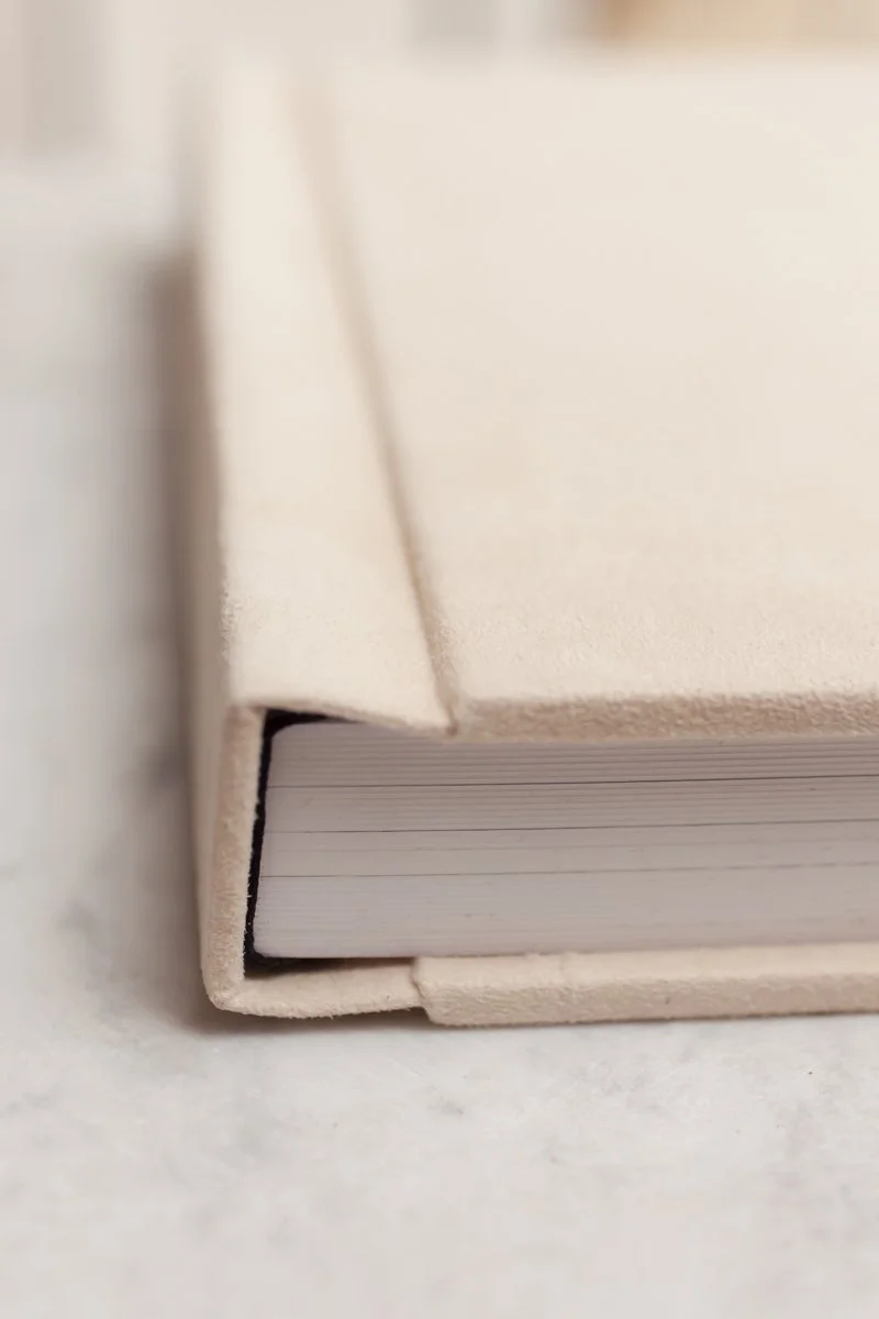 Nahaufnahme eines weißen Buches oder Notizblocks mit gefüttertem Einband, der auf einer weißen Oberfläche liegt.