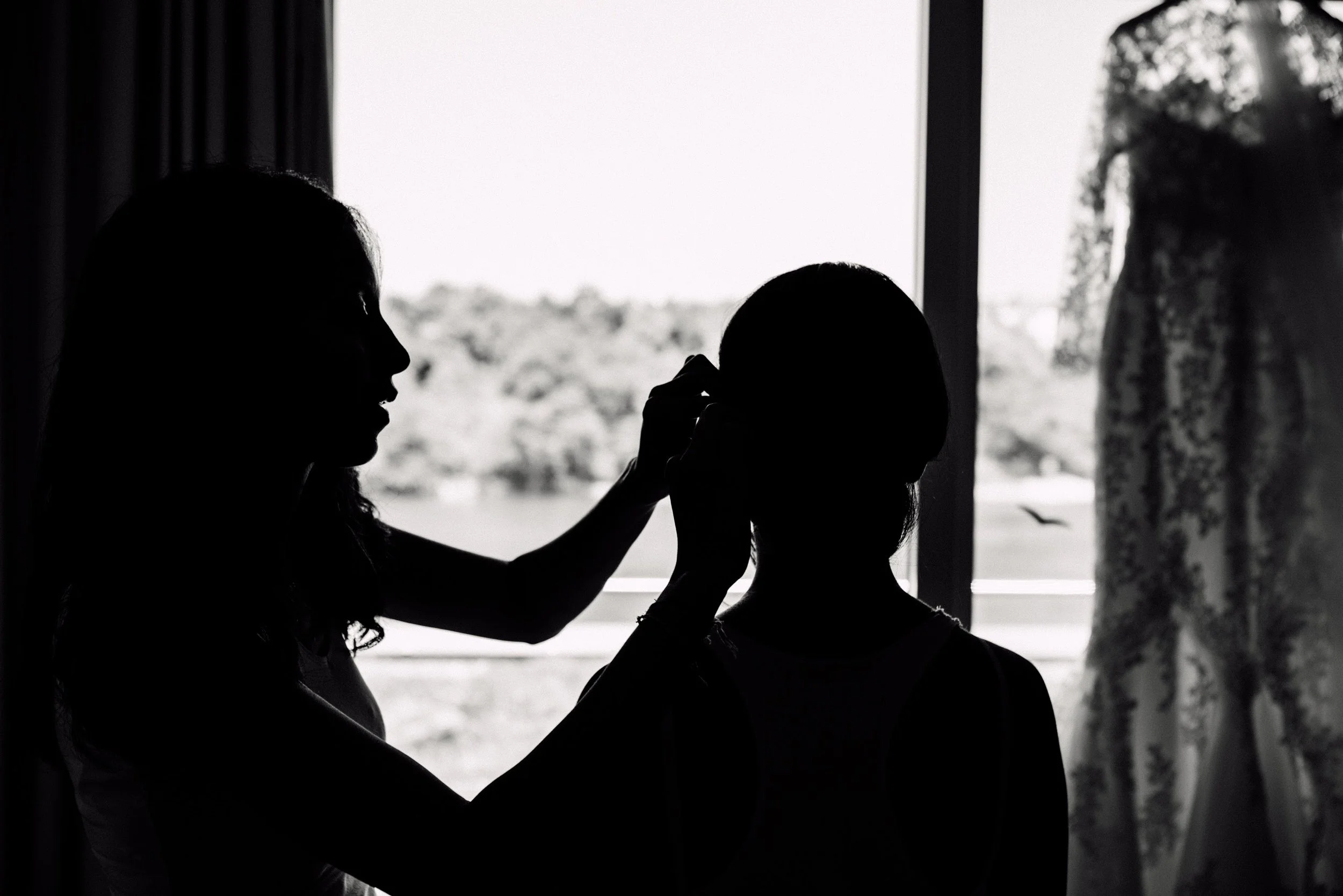 Silhouette einer Frau, die einem Kind den Rücken streicht, vor einem Fenster mit Blick ins Freie, schwarz-weiß Aufnahme