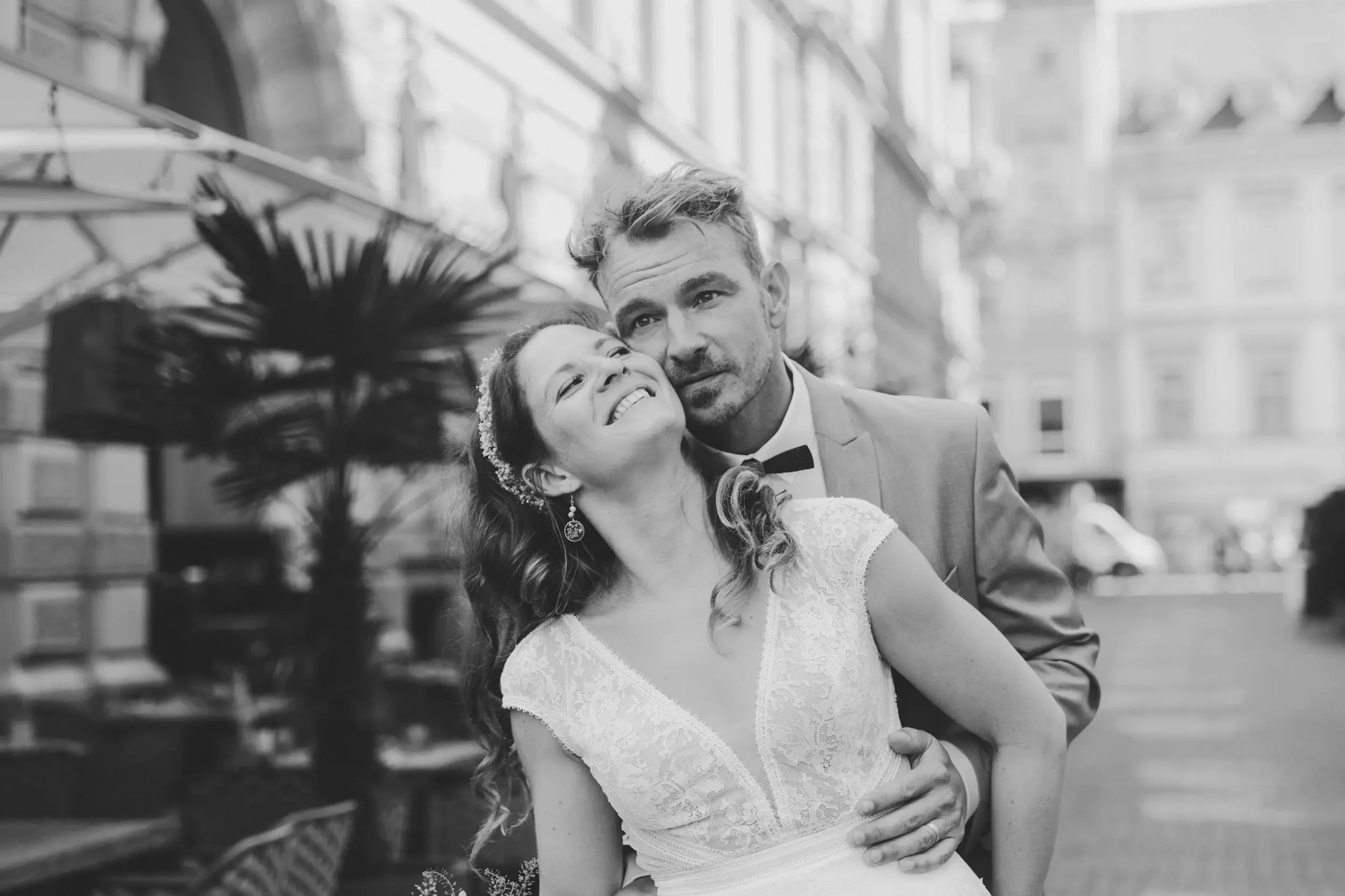 Ein Paar bei einer Hochzeit, das sich liebevoll umarmt, im Hintergrund ein moderner Innenraum mit großen Fenstern.