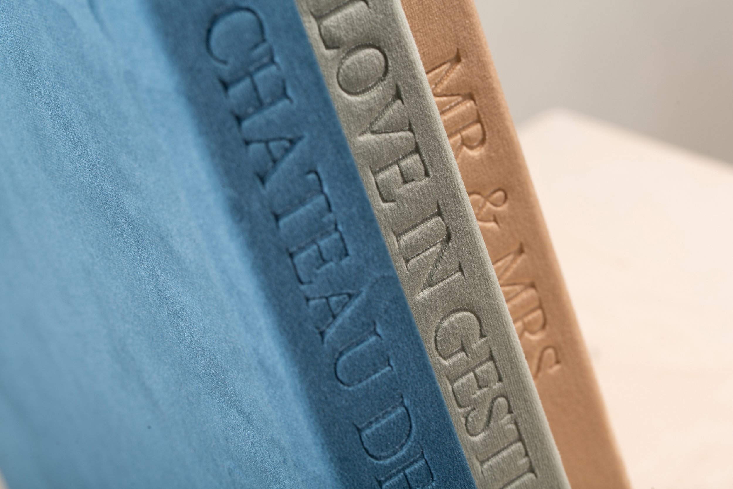 Nahaufnahme von drei Zuckerwürfeln in Blau, Grau und Braun mit eingedrückten Buchstaben auf ihrer Oberfläche.