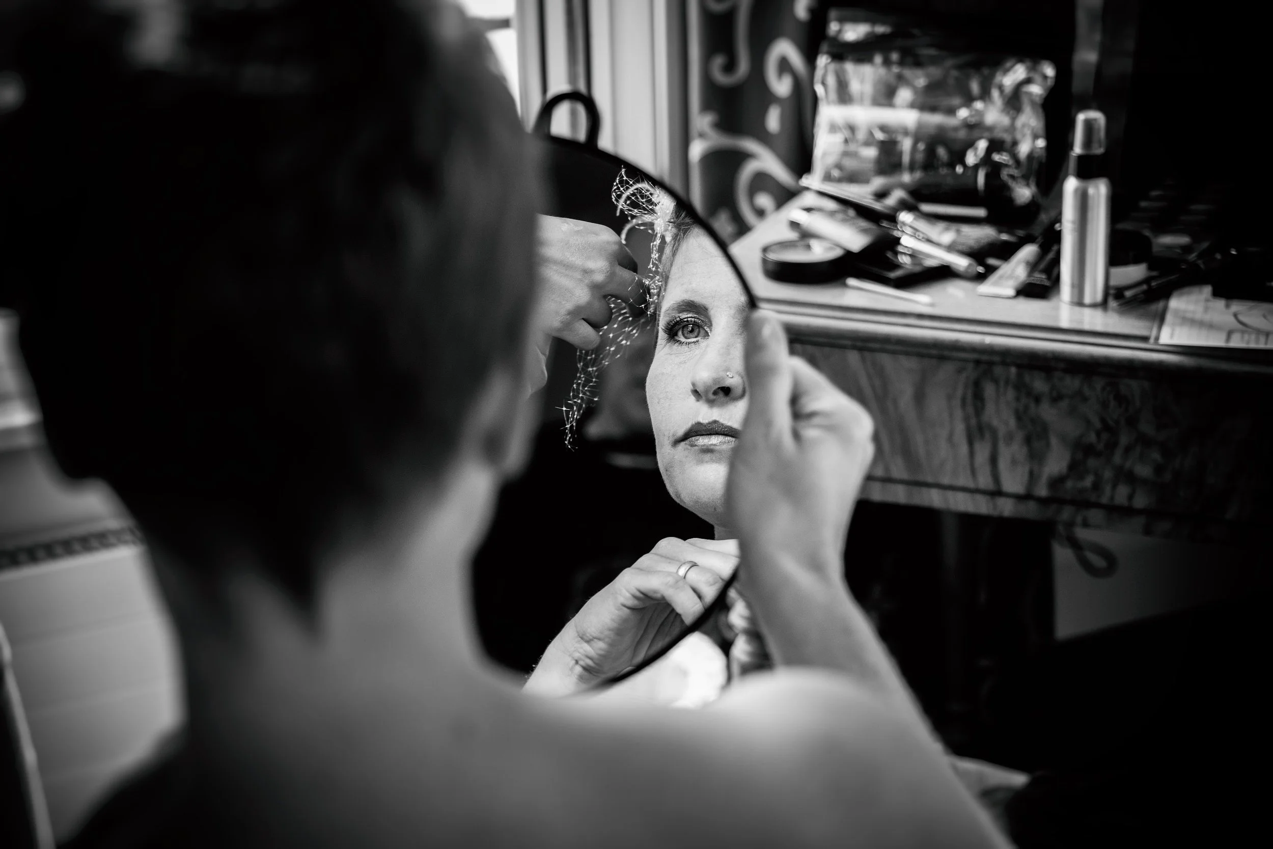 Frau beim Make-up, Spiegel und Schminkutensilien sichtbar.
