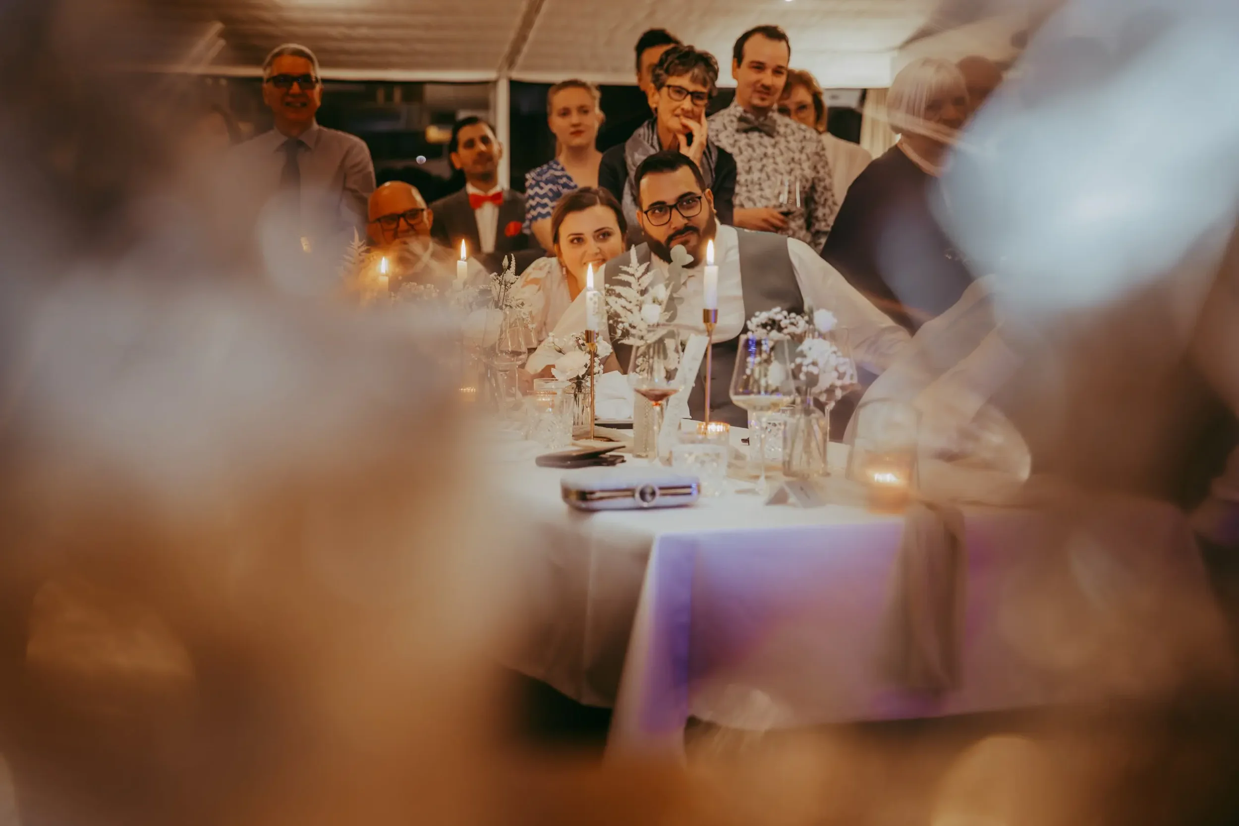 Menschen genießen eine Feier mit Kerzen, Wein und festlicher Kleidung, tendenziell ein elegantes Abendessen oder eine Feier in einem festlichen Raum.