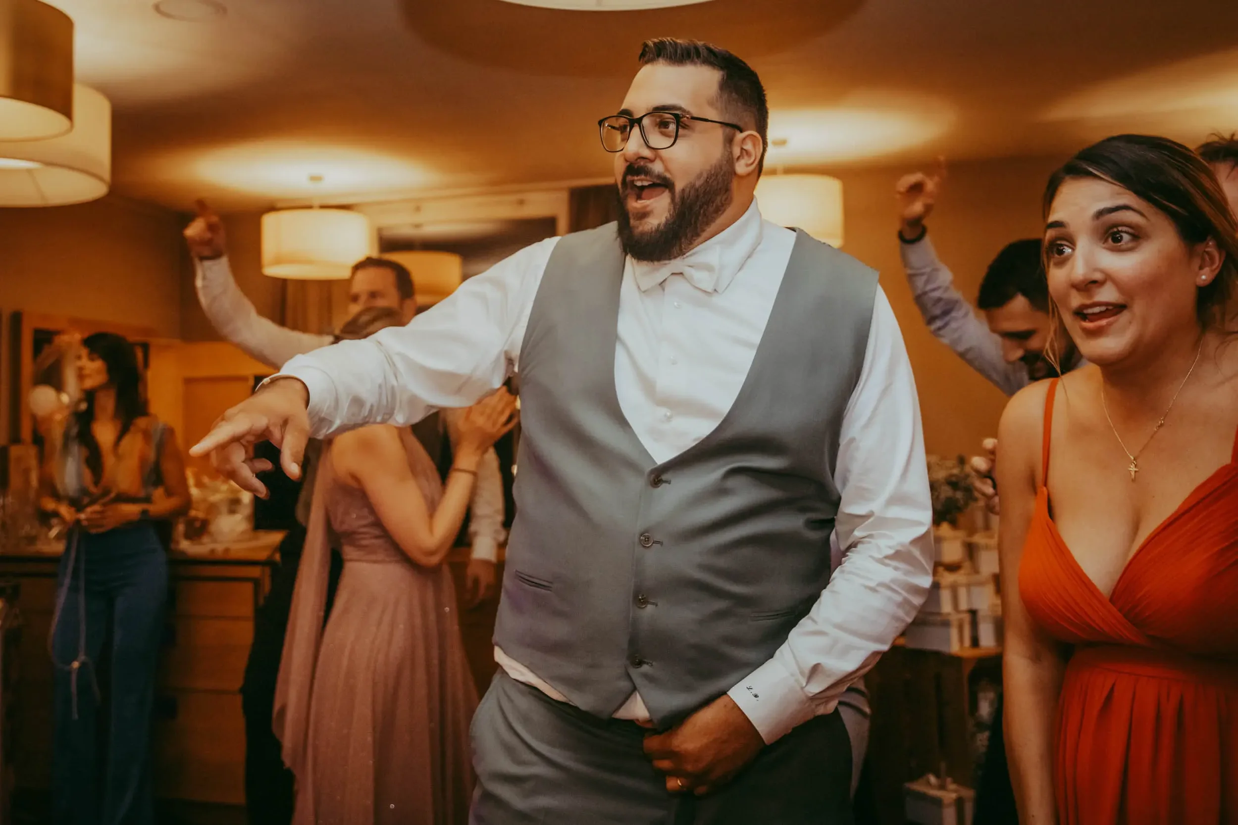 Jemand tanzt auf einer Party in einem Wohnzimmer, umgeben von anderen Gästen.