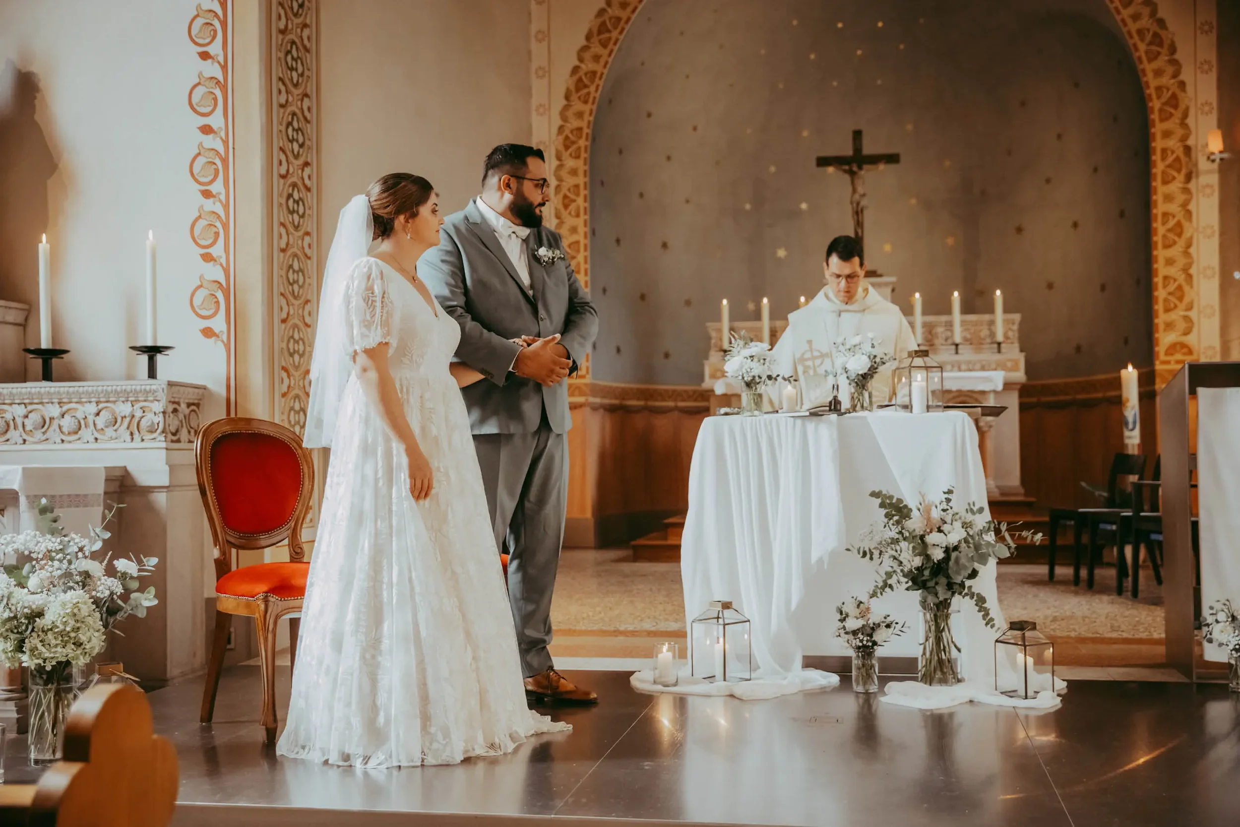 Ein Brautpaar bei einer kirchlichen Hochzeitszeremonie, stehend vor einem Priester, in einer kirchlichen Umgebung mit Kerzen und Blumen