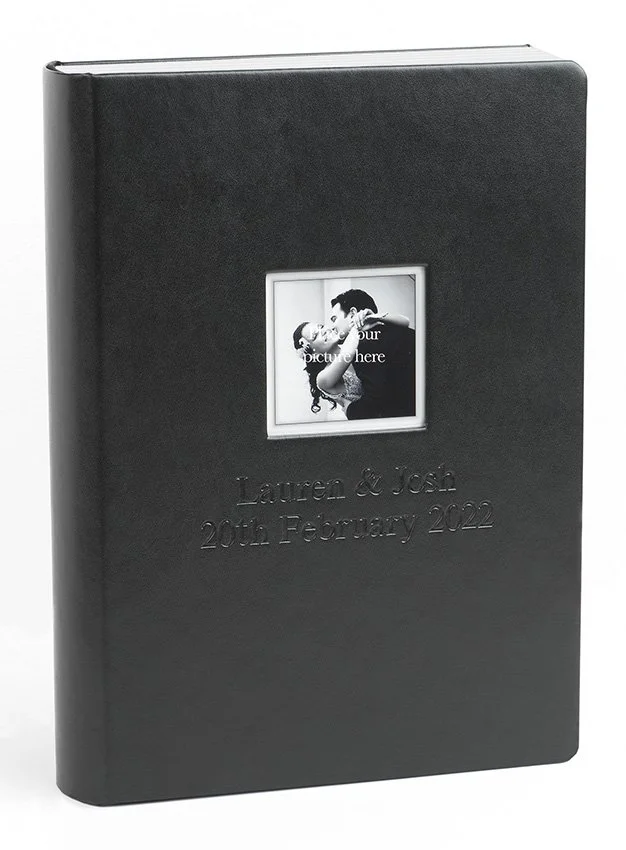Schwarzes Fotoalbum mit gravierten Namen "Lauren & Josh" und Datum "20. Februar 2022" sowie einem kleinen quadratischen Platzhalter für ein Foto, das derzeit leer ist.