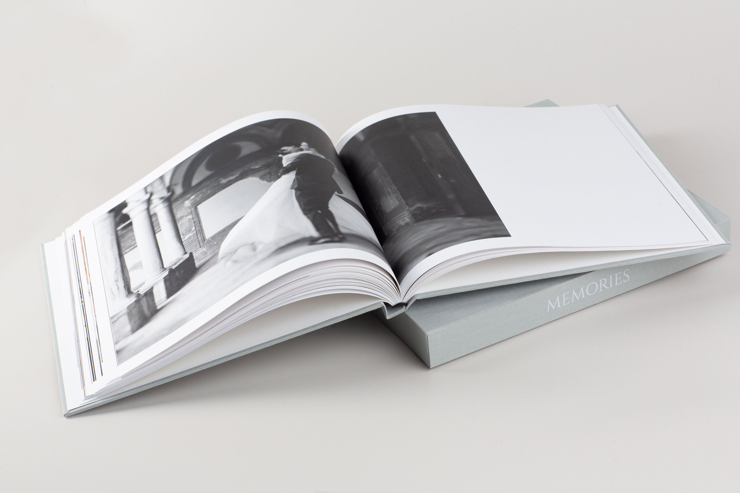 Ein geöffnetes Fotobuch mit Schwarz-Weiß-Fotografien liegt auf einem weißen Tisch.