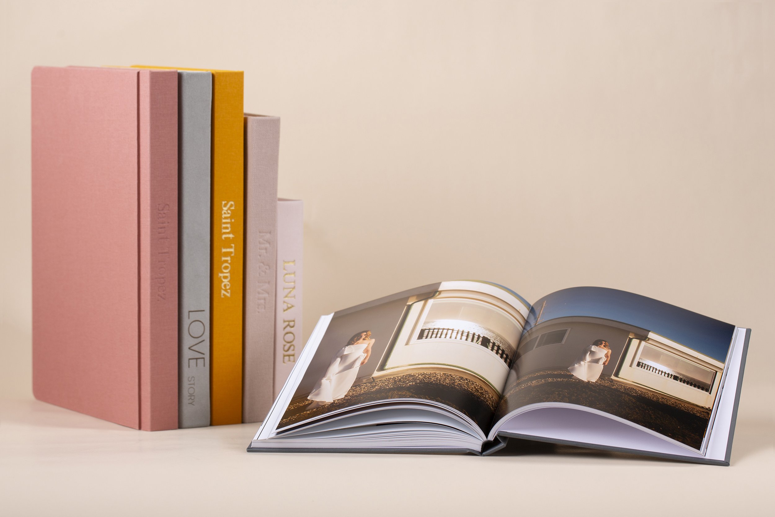Offene Buch mit Innenansicht, daneben stapelbare Bücher in Pastellfarben.