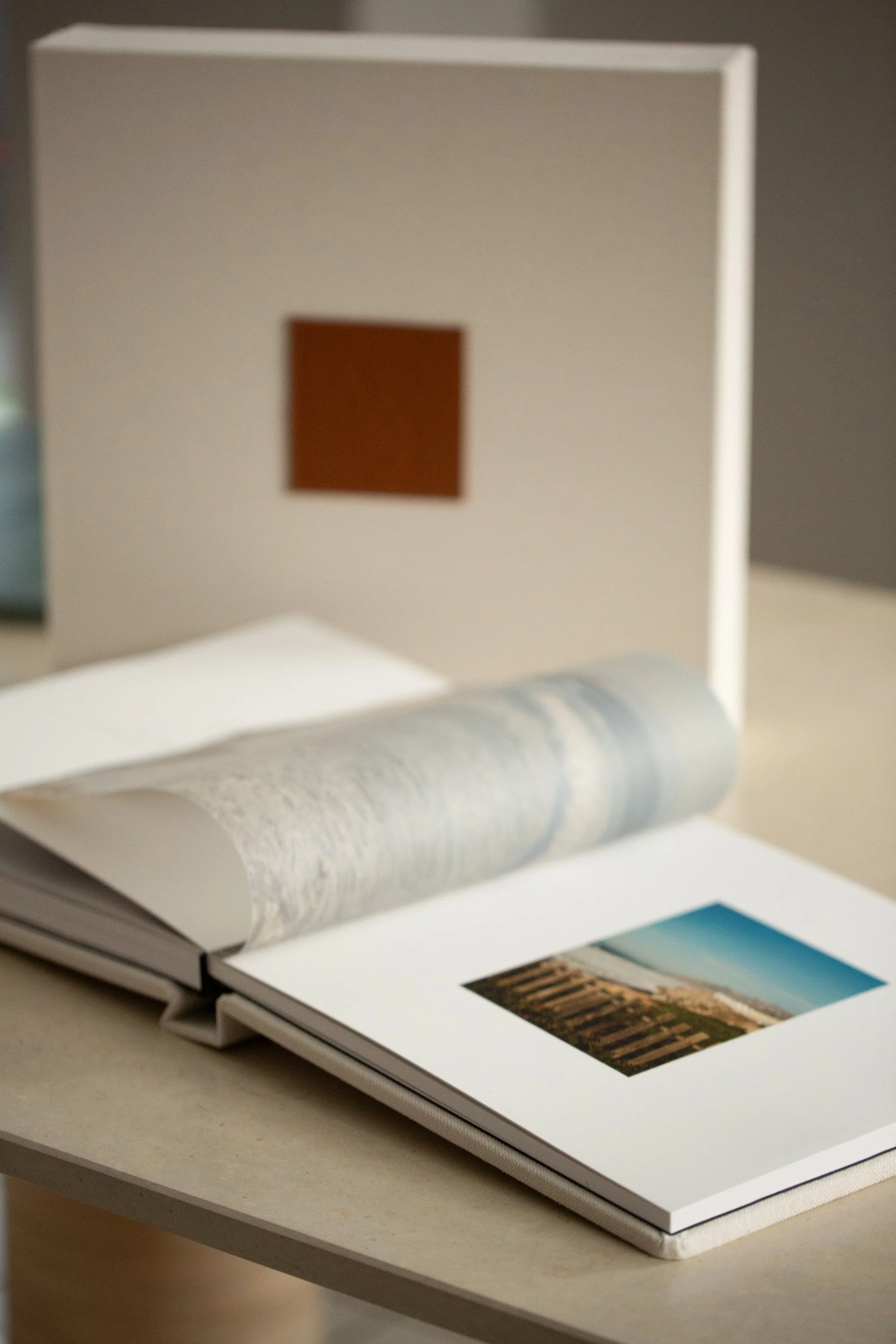 Offene Fotobücher mit Landschaftsansichten auf einem Tisch, teilweise umgeblättert.