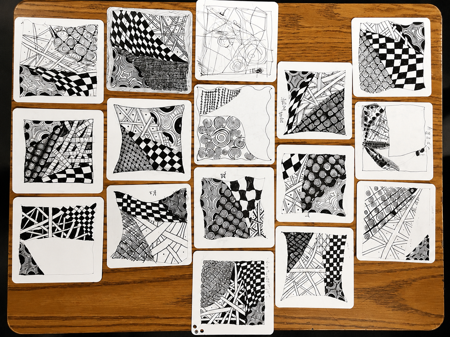 A collection of 15 black and white abstract patterned cards with various geometric and organic designs, arranged on a wooden table.
