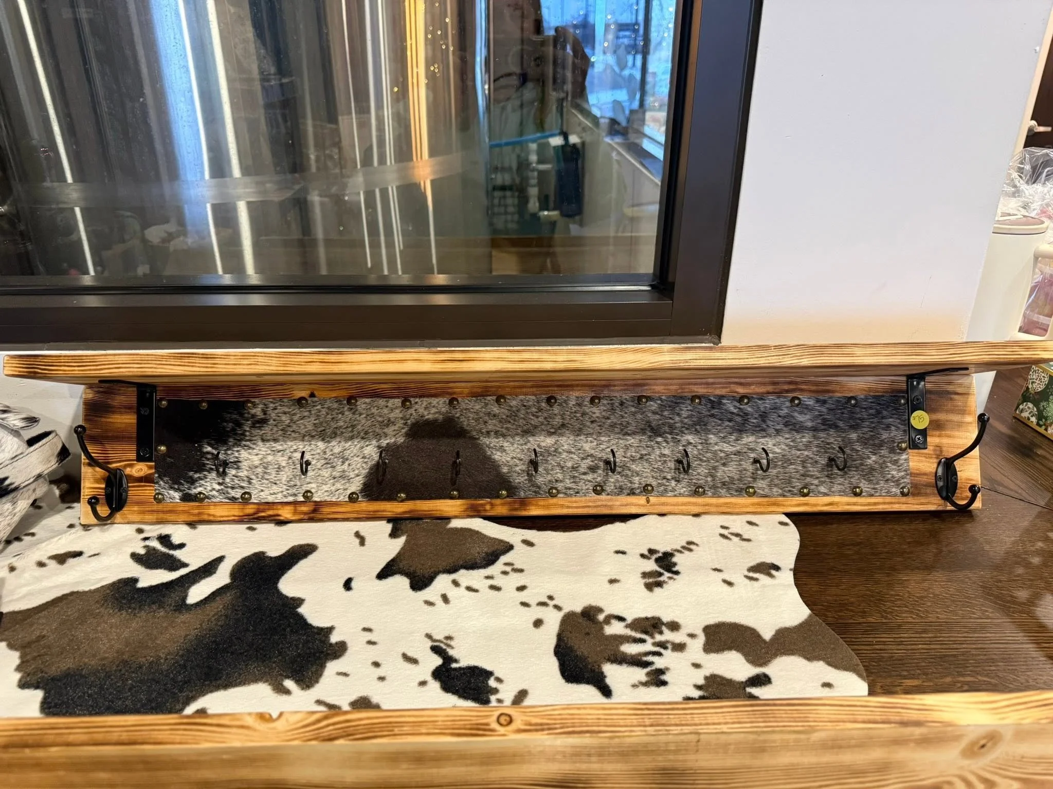 Wooden and metal display stand with hooks, placed on a black and white animal print rug.