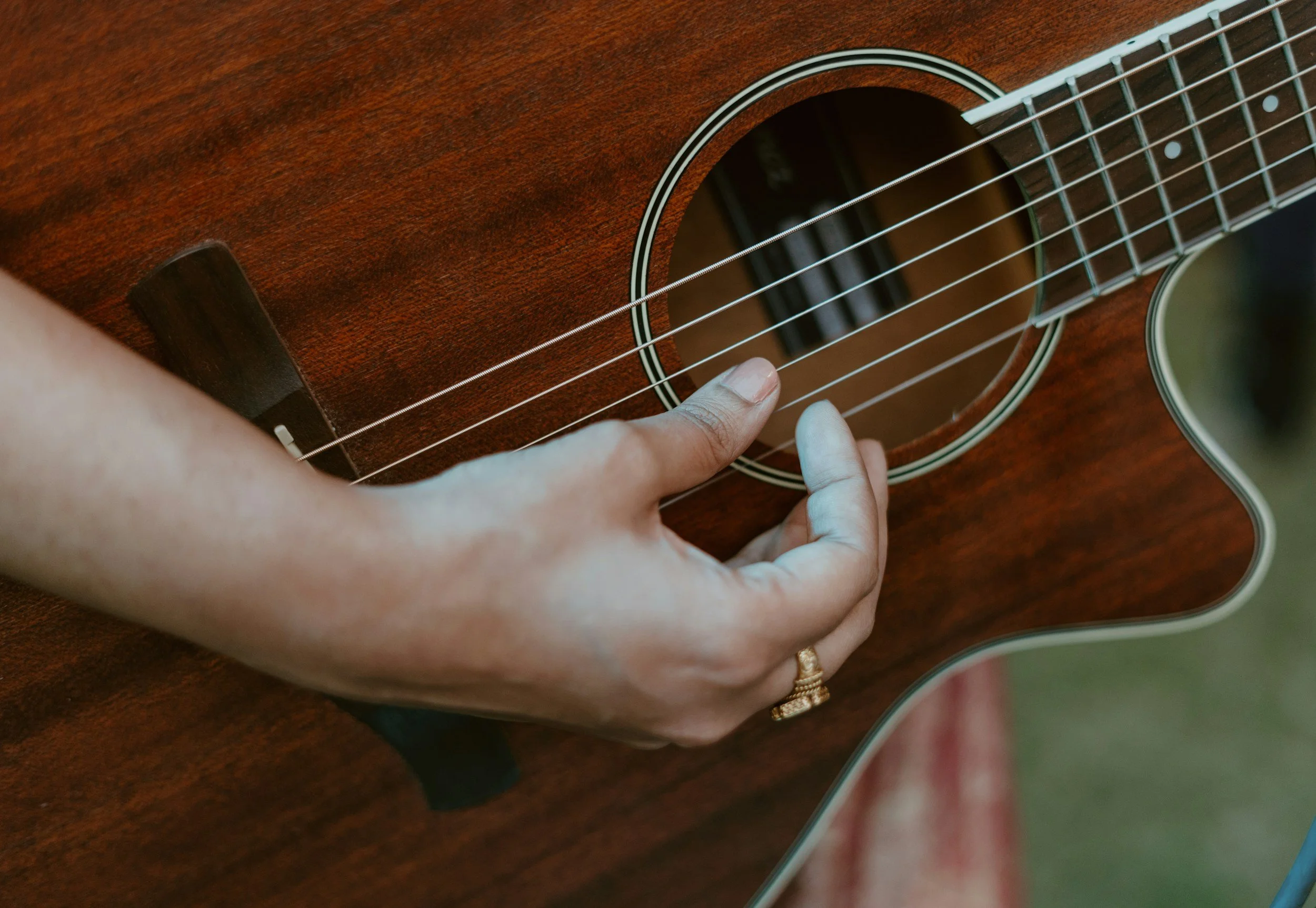 Close-up of a hand playing an acoustic guitar on a wooden surface