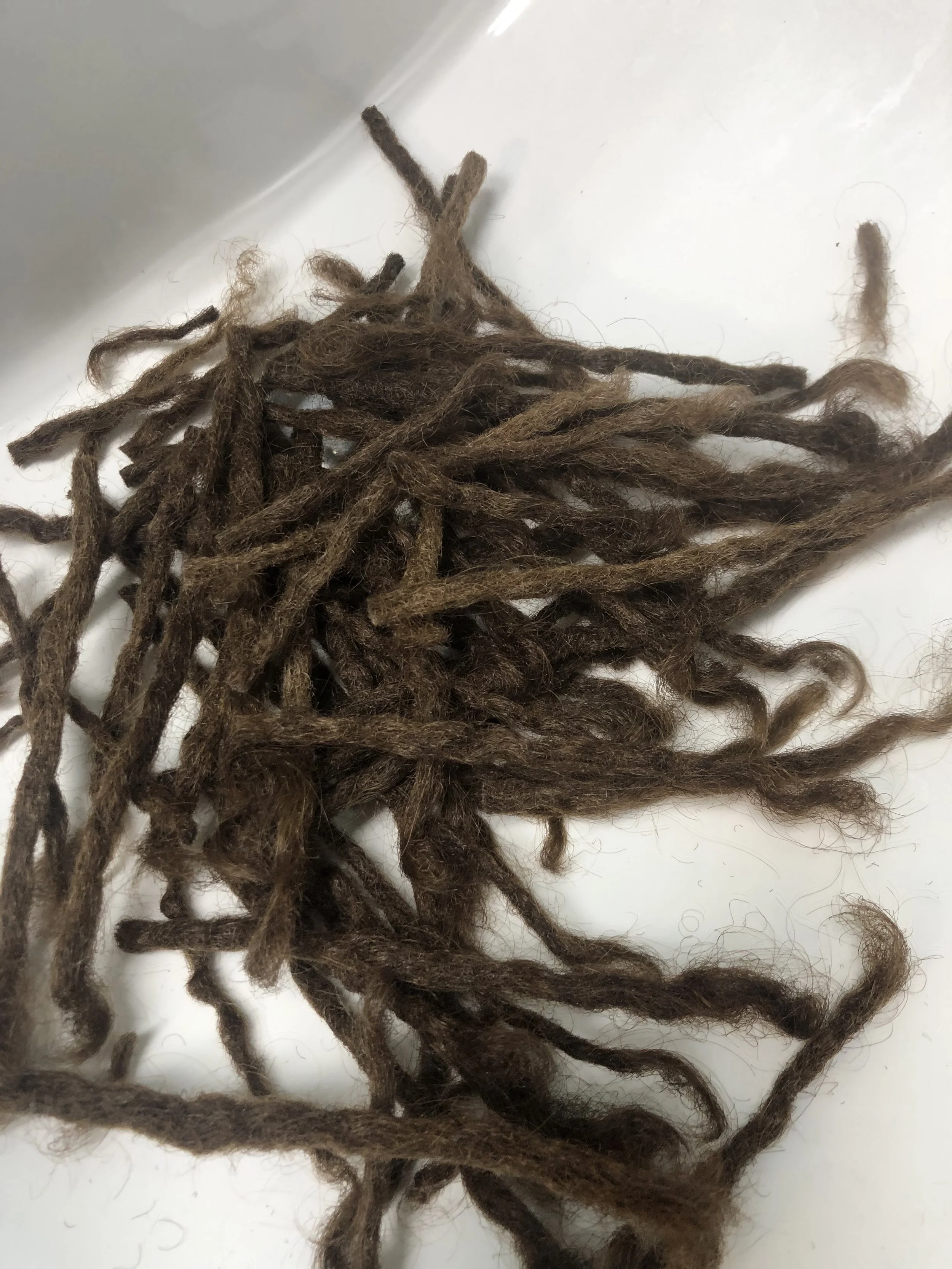 Multiple brown dreadlocks hair extensions arranged on a white surface.