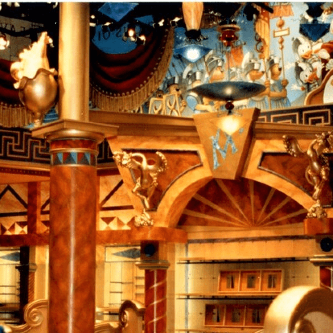Decorative interior with columns, gold accents, and artistic murals, inspired by ancient Greek mythology.
