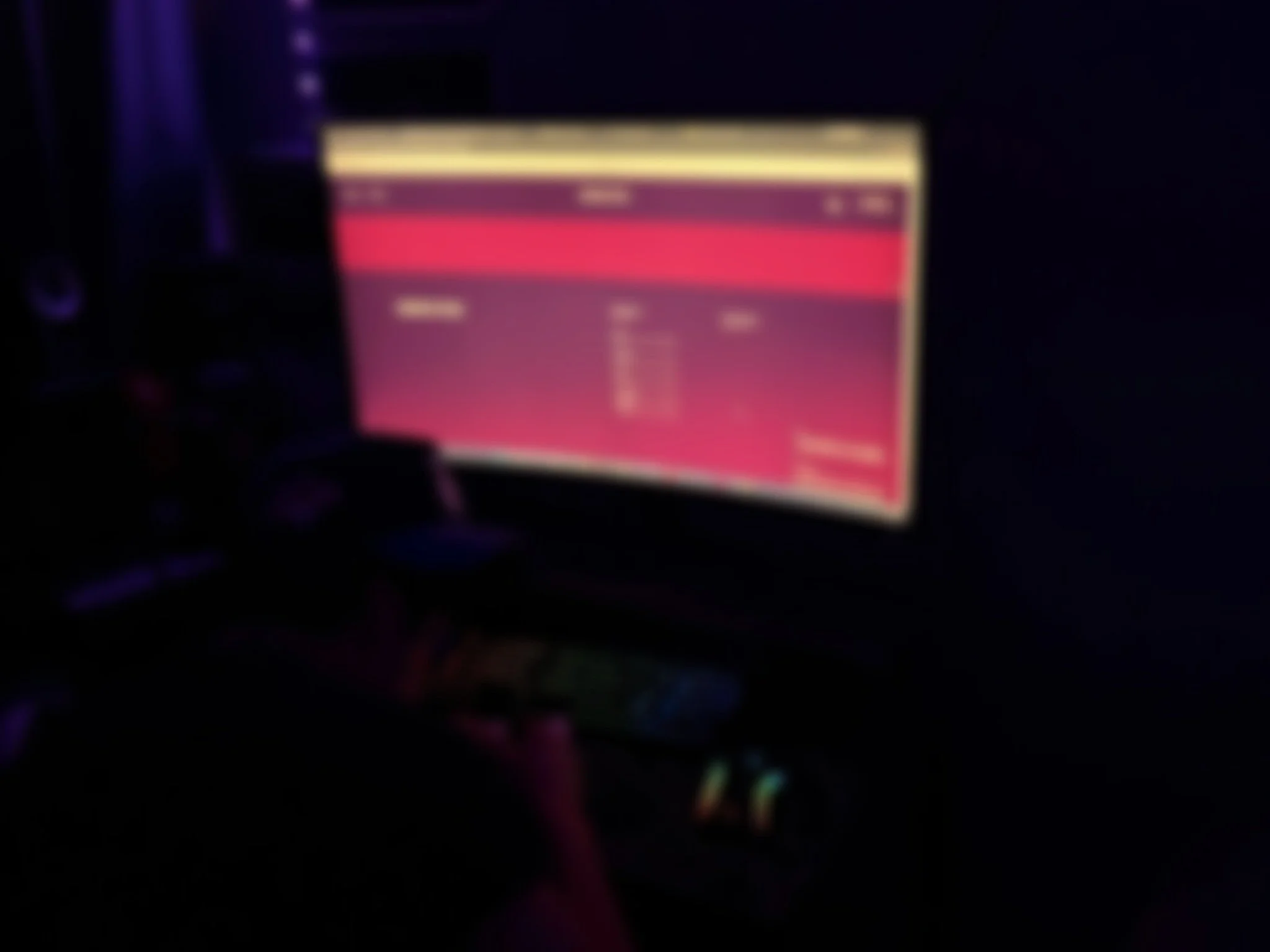 A blurry image featuring a computer monitor or screen with a pinkish-red display.
