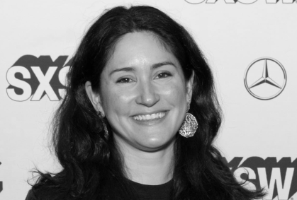 A woman with dark wavy hair smiling at a red carpet event with SXSW, Mercedes-Benz logos in the background.