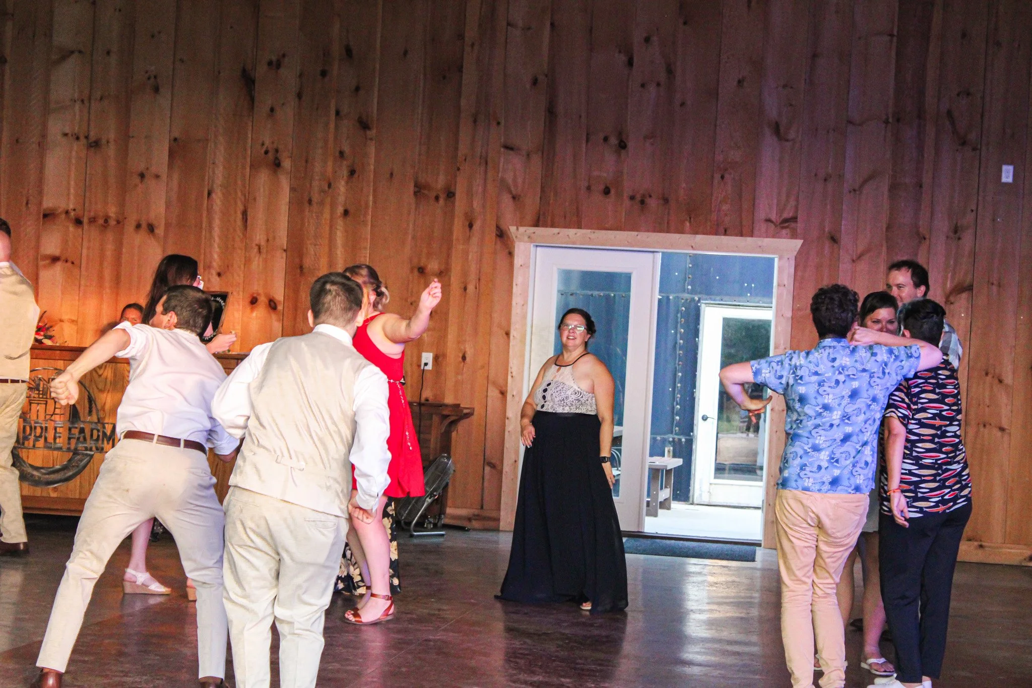 People dancing and socializing in a rustic wooden indoor space at a party or celebration.