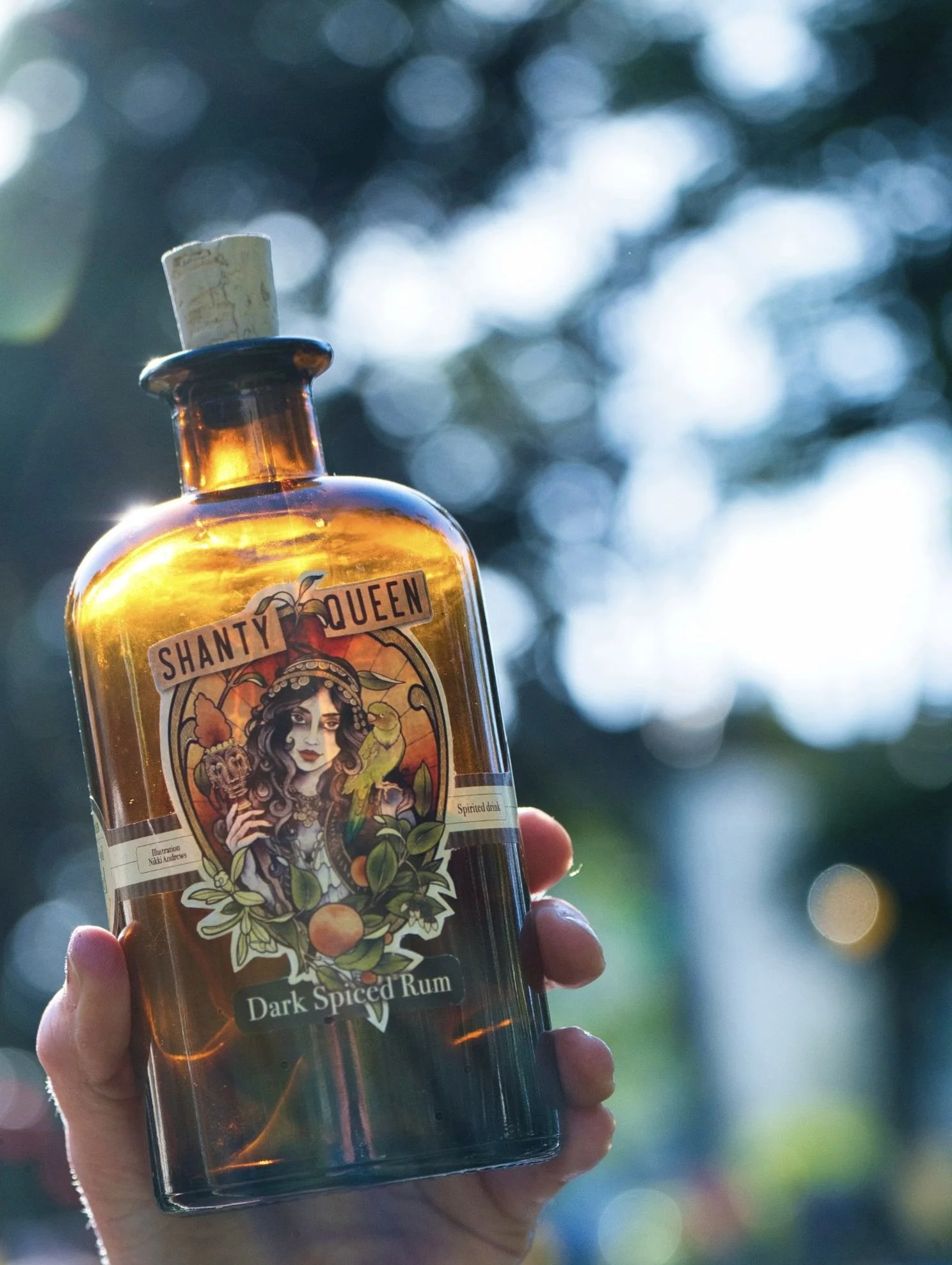 hand holding bottle of shanty queen rum with sunlight shining through