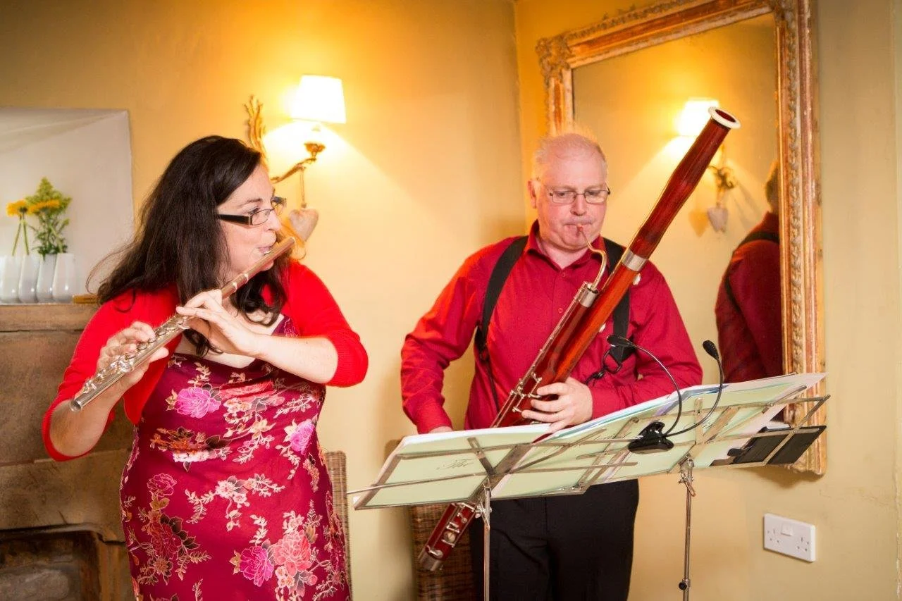 Katy playing flute and Miles playing Bassoon in matching smart red outfits