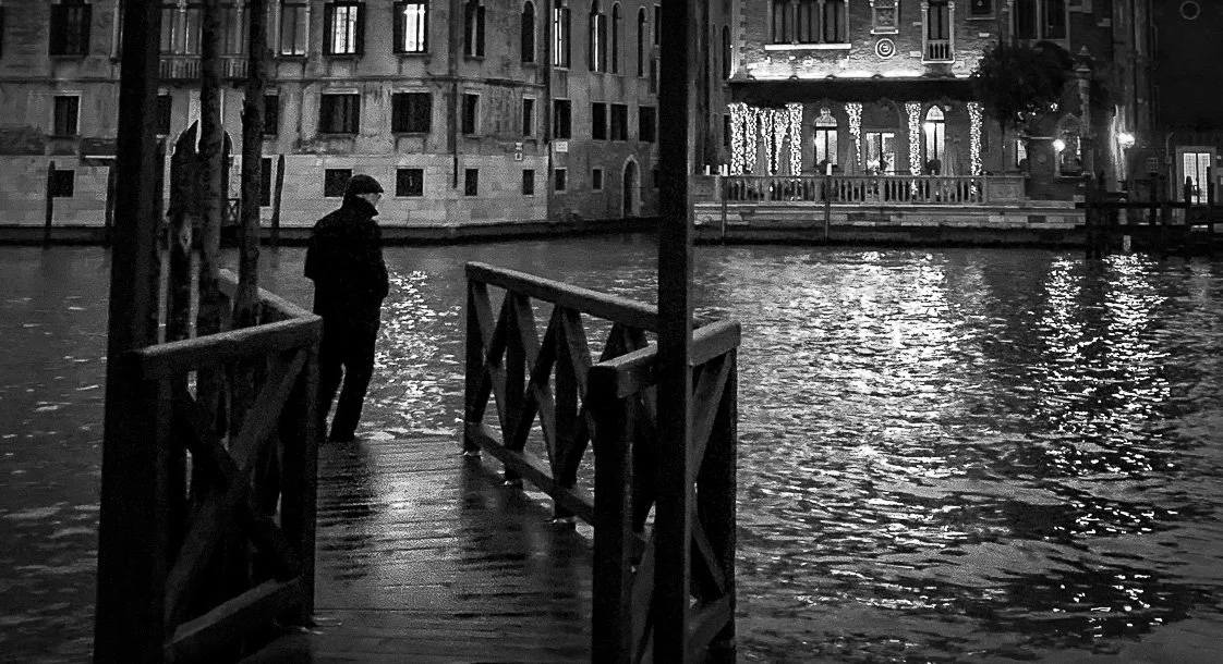 A man waits on the pontoon by the grand canal at San Samuele, Venice