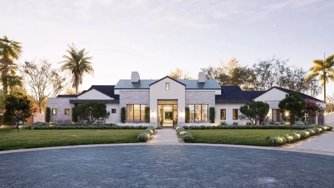 Large modern house with white exterior, surrounded by greenery and palm trees, under a clear sky.