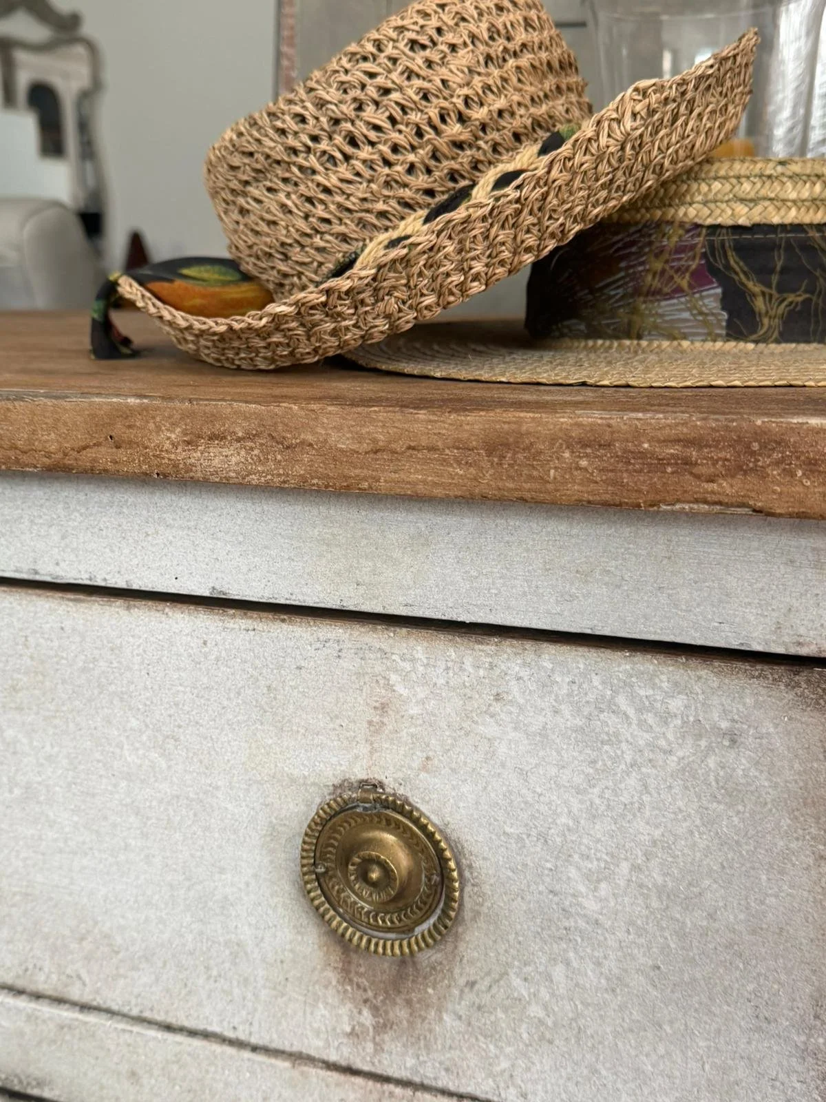 Cappelli di paglia e un cassettone antico con manico di metallo, sulla superficie di legno rustico.