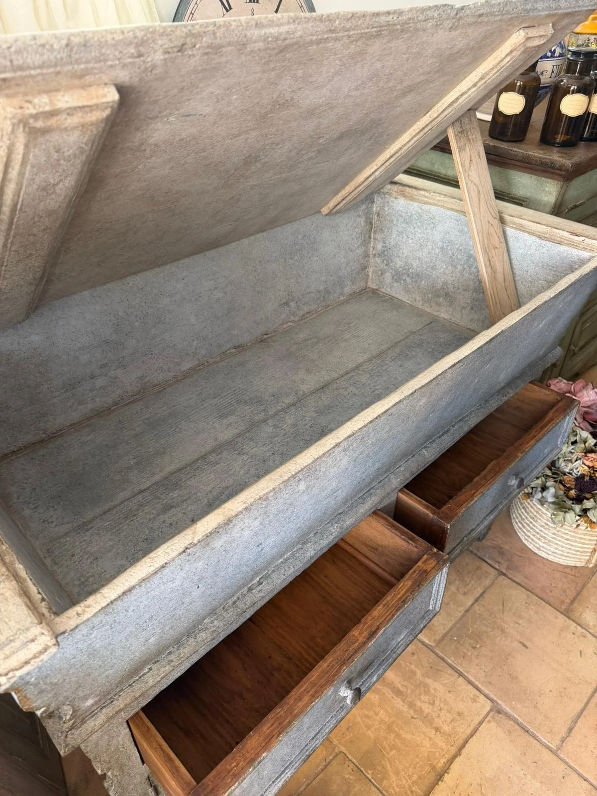 Cassa in pietra con cassetti pieni di oggetti, in un ambiente domestico.