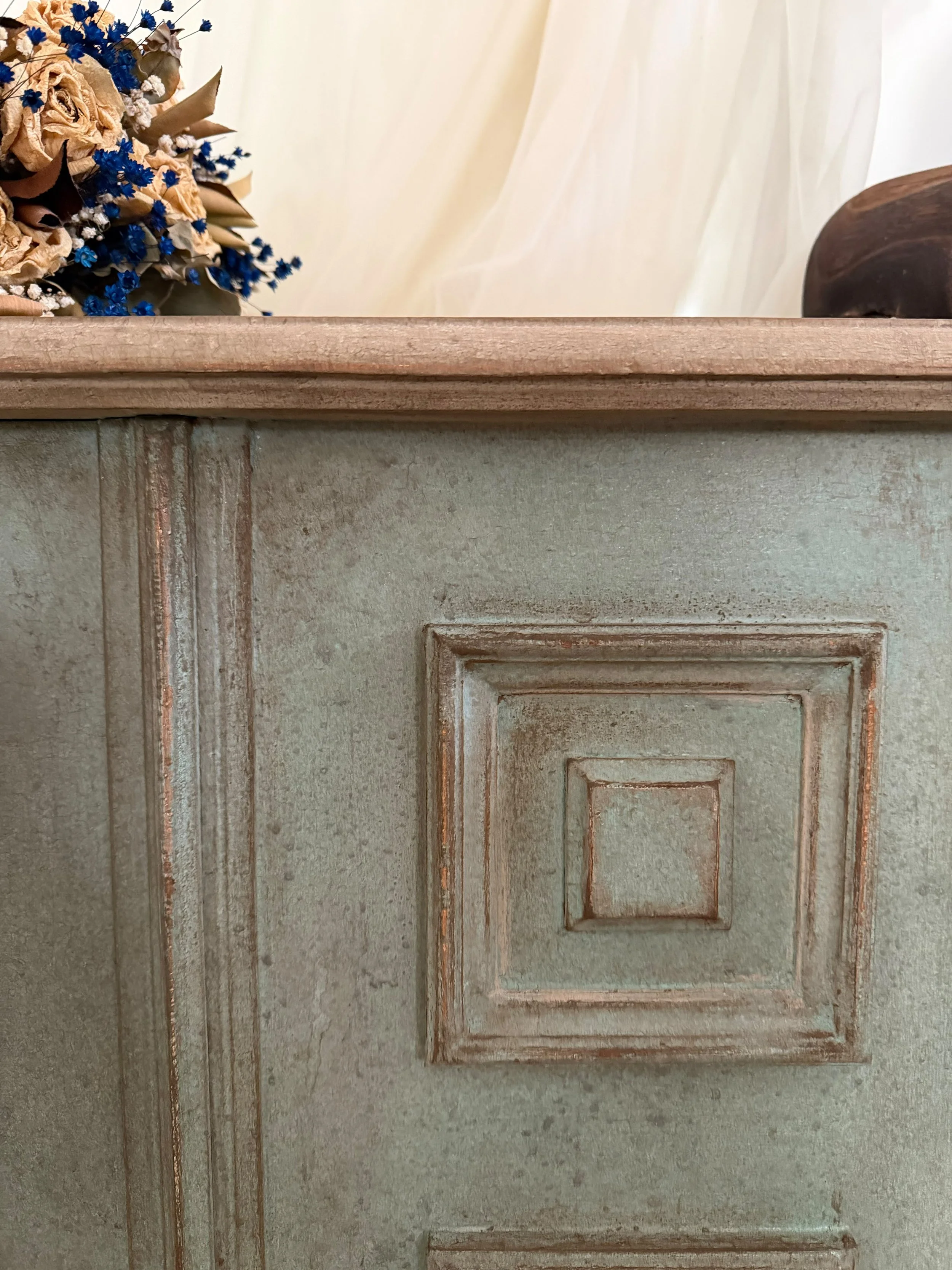 Porta in legno con dettagli di rilievo e colore verde invecchiato, vista frontale.