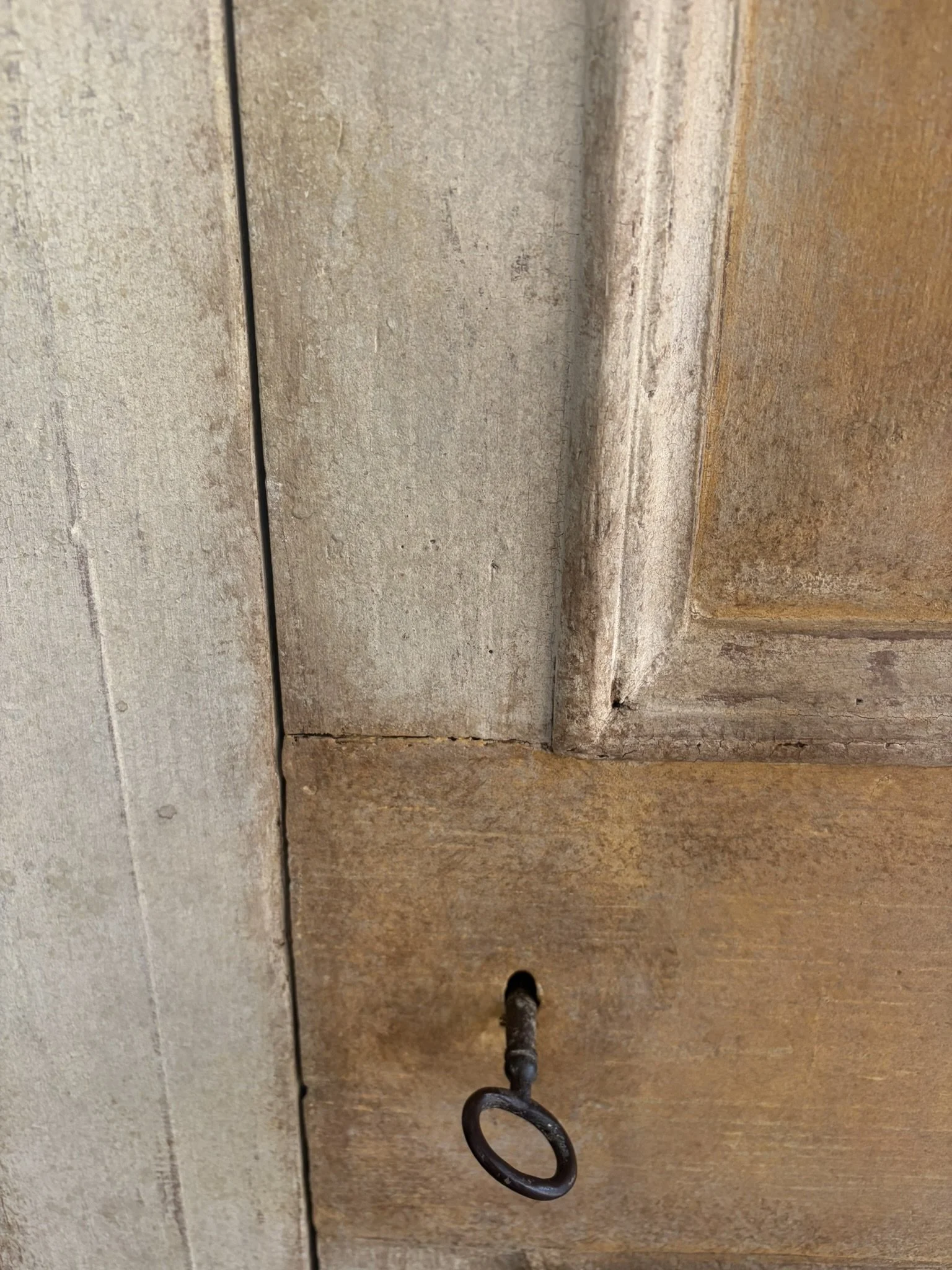 Dettaglio di una chiave in ferro inserita in una serratura di una porta in legno.
